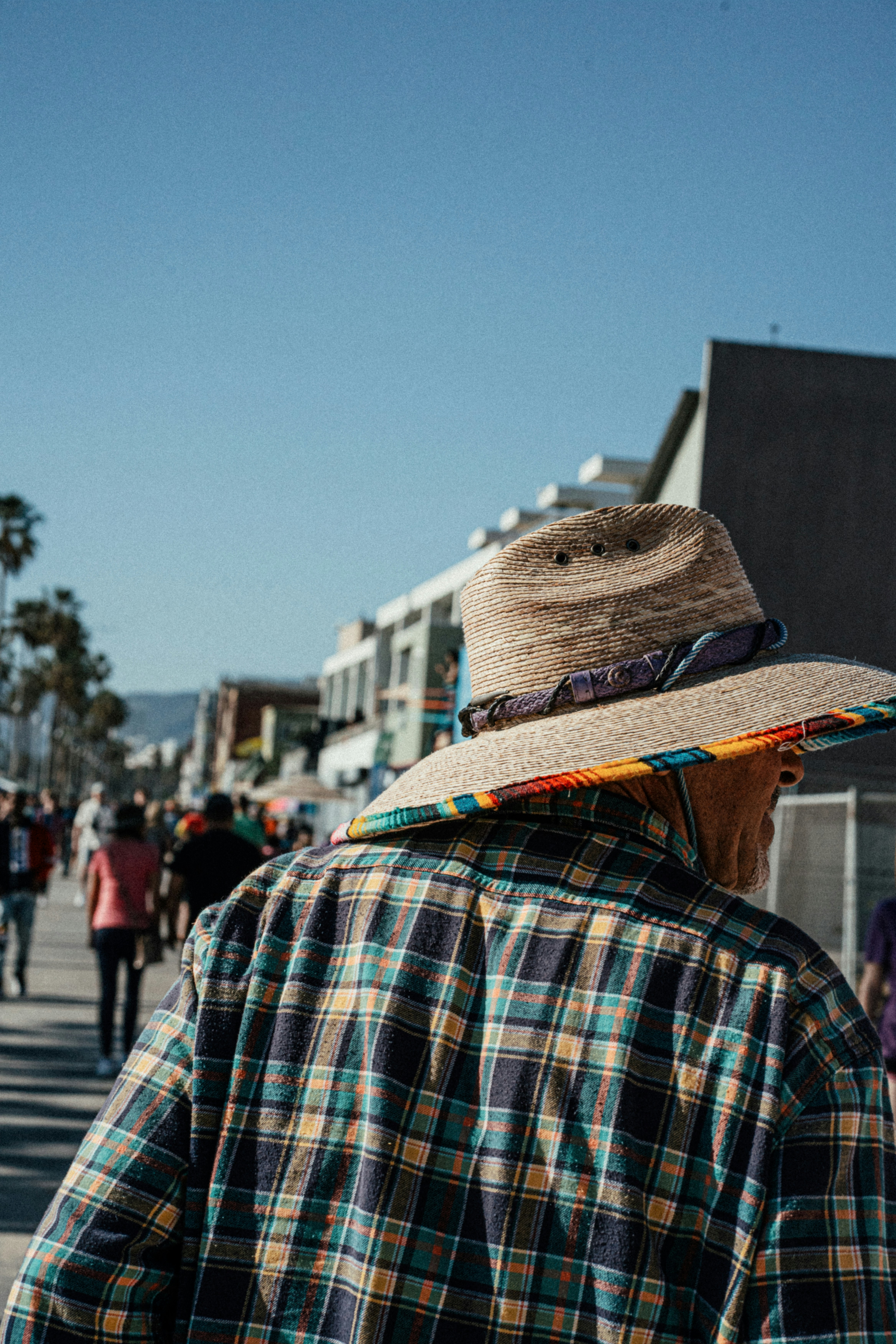 Woman browsing clothes racks at an outdoor flea market in California wearing stylish sunglasses and hat