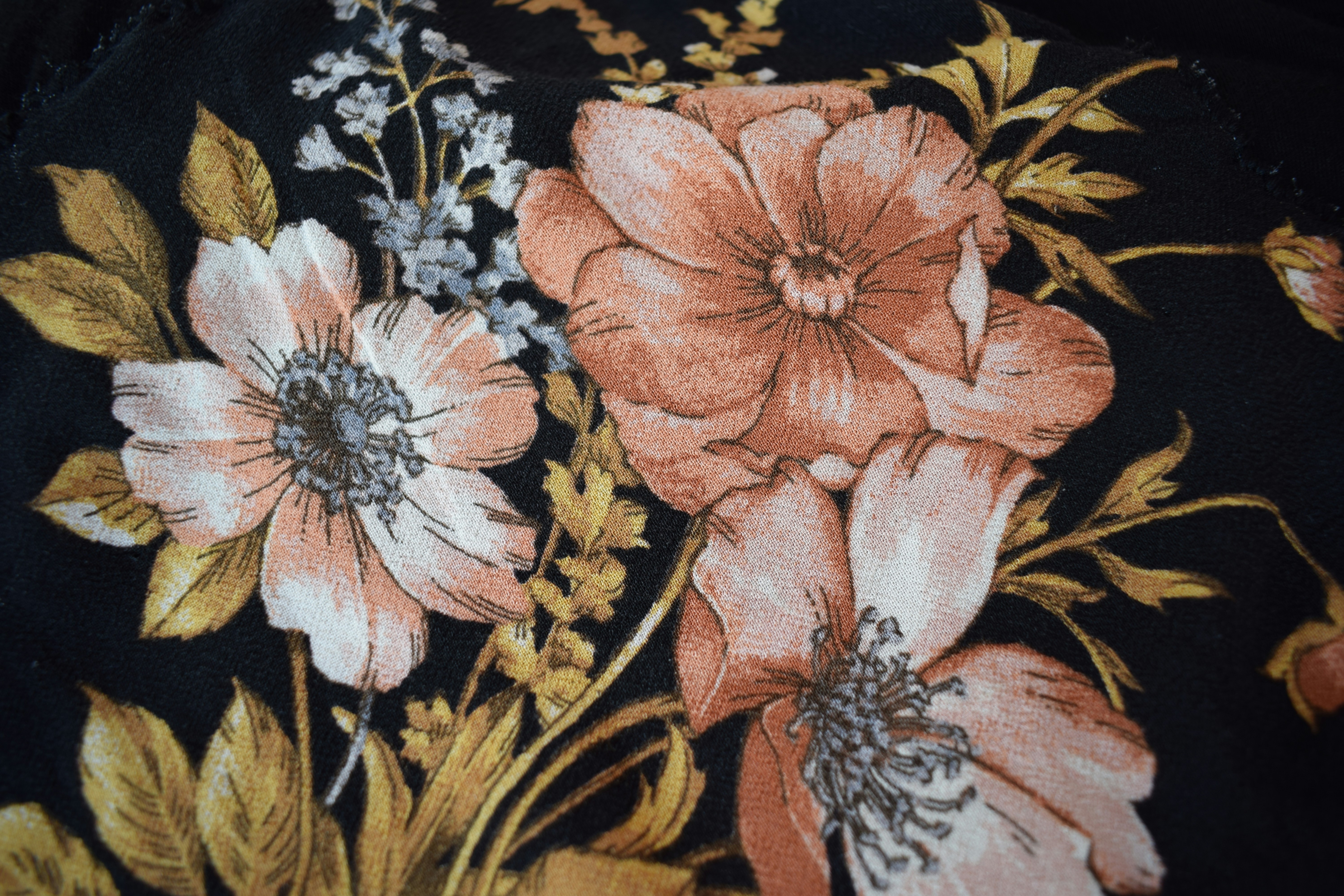 close up detail of colorful floral embroidery on a denim jacket or tunic, bohemian fashion style