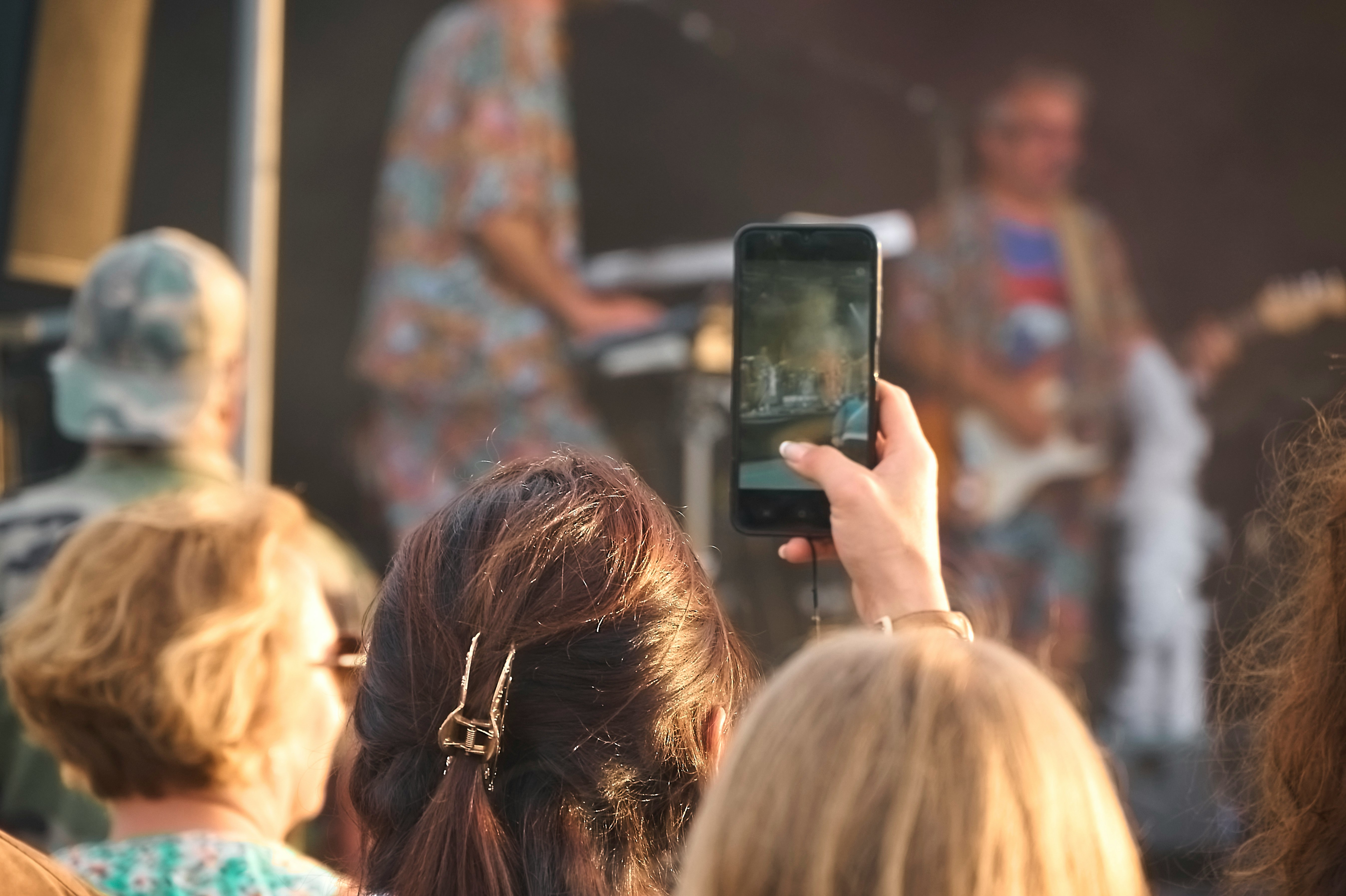 crowd of people at a concert holding up smartphones to record