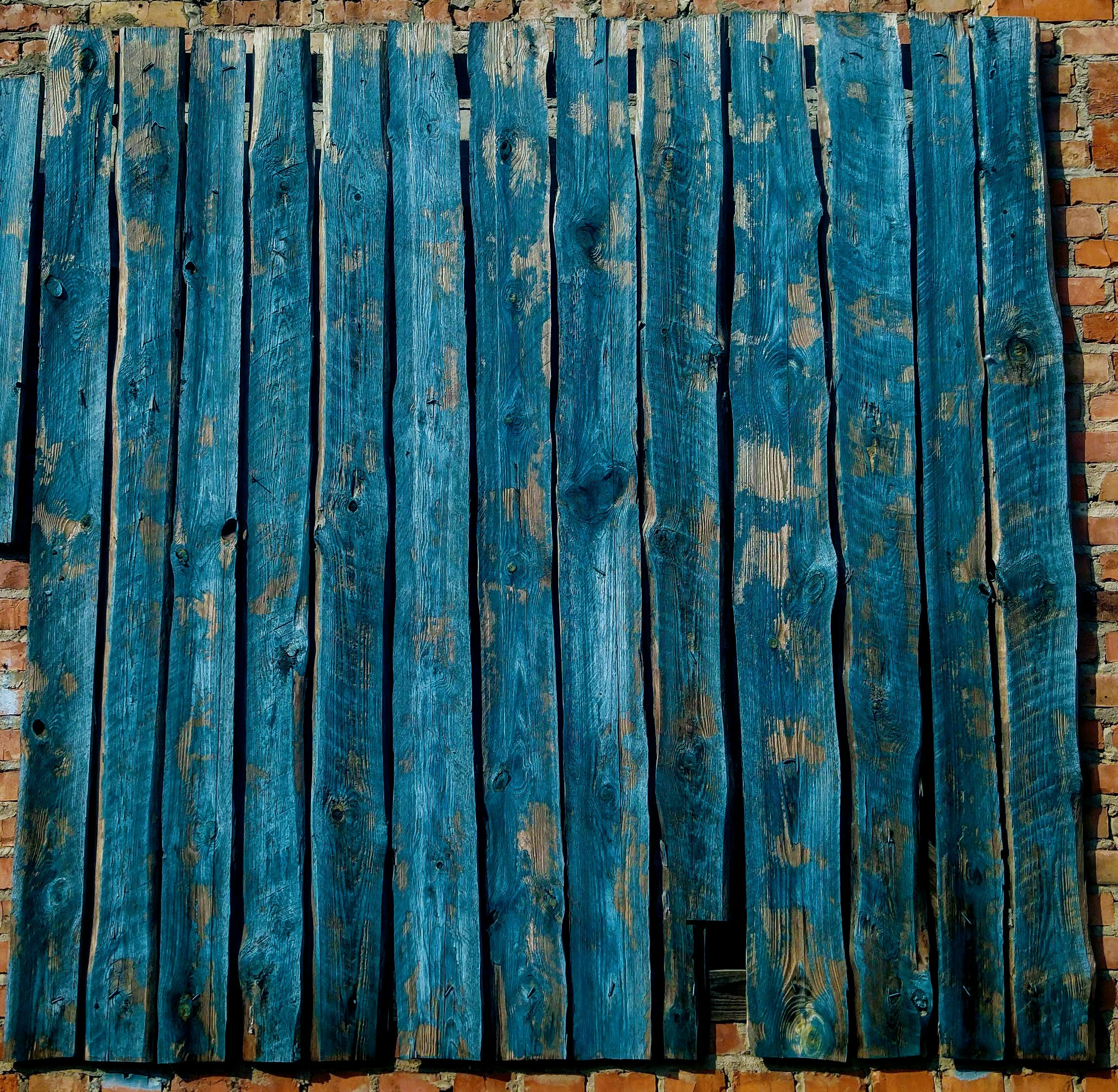 High-angle textural shot of a stack of folded jeans in various shades of blue, from indigo to acid wash, placed on a wooden table.