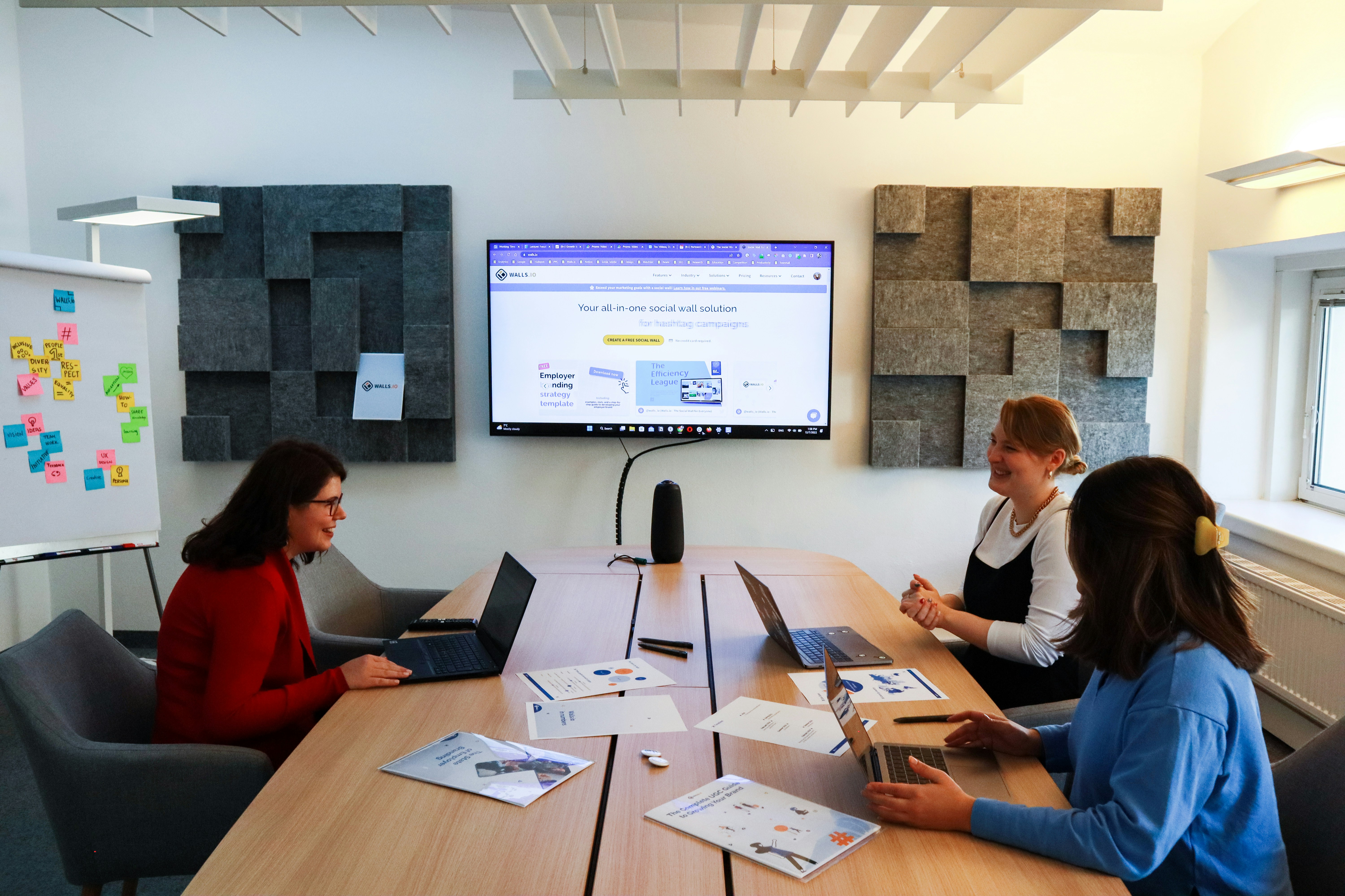 Three diverse business colleagues pointing at a laptop screen in a modern bright office discussing data