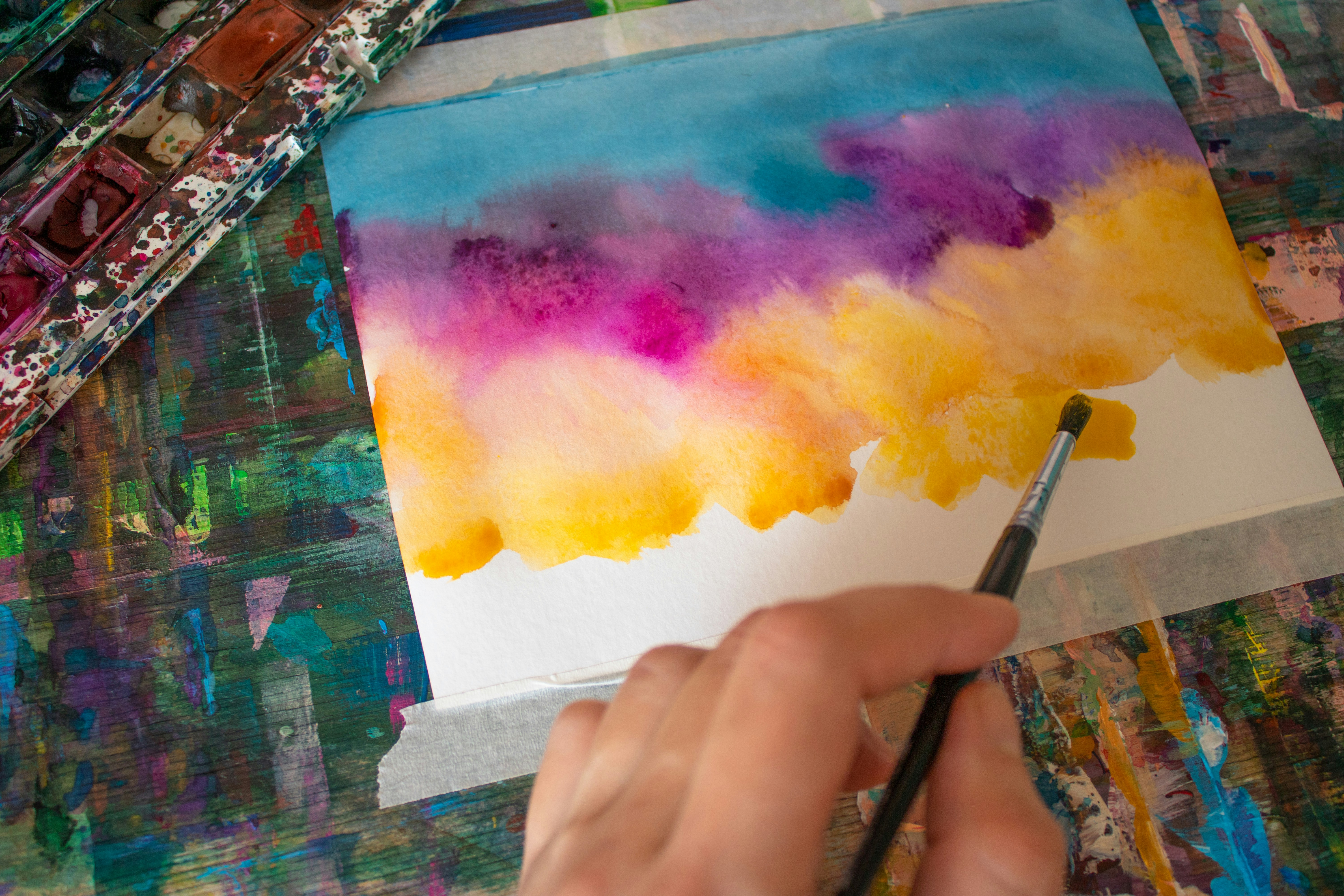 Close up of a painter's hands mixing colors on a palette in a bright studio