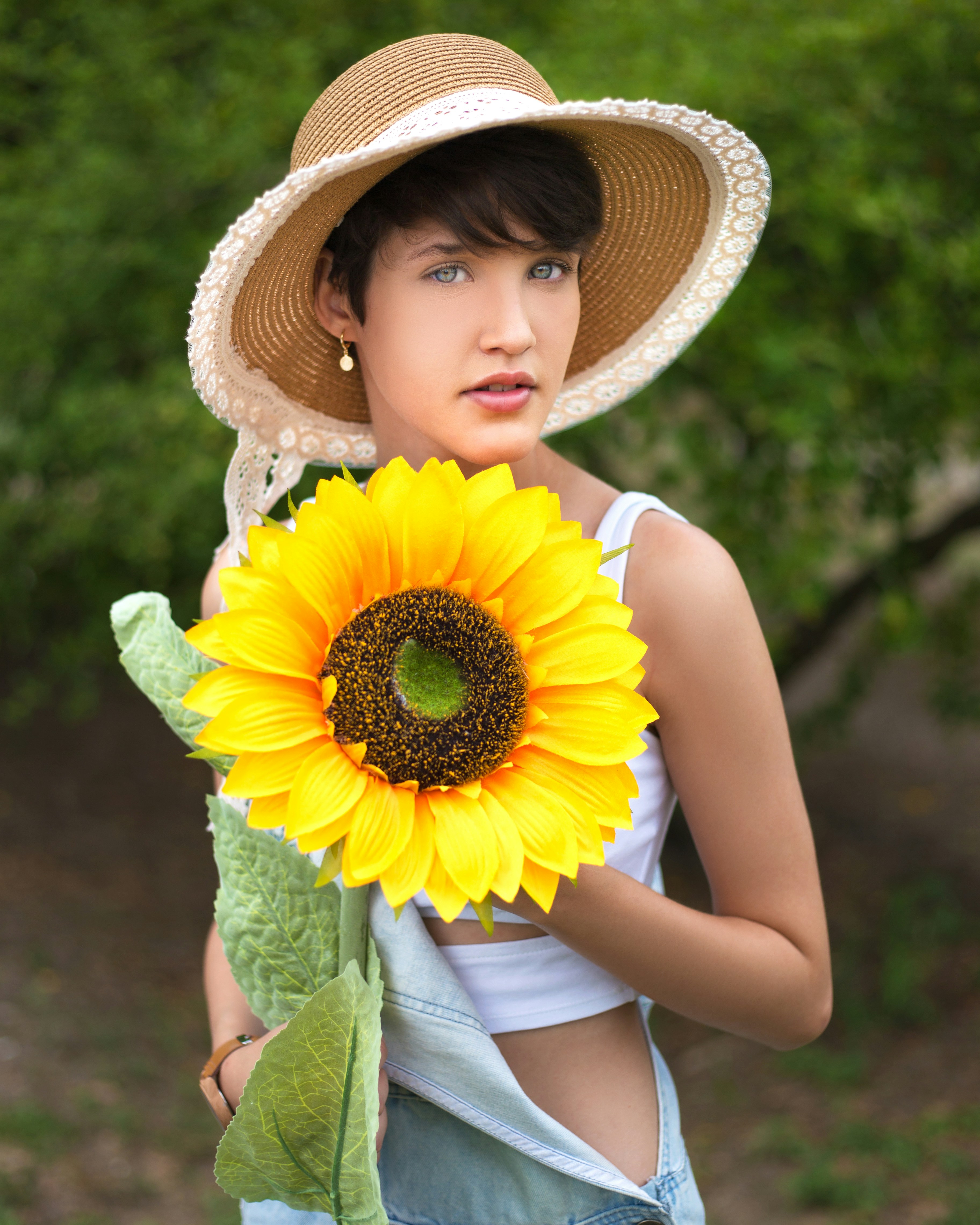 Femme grande taille portant un chapeau et des accessoires bohèmes souriant dans un champ de fleurs