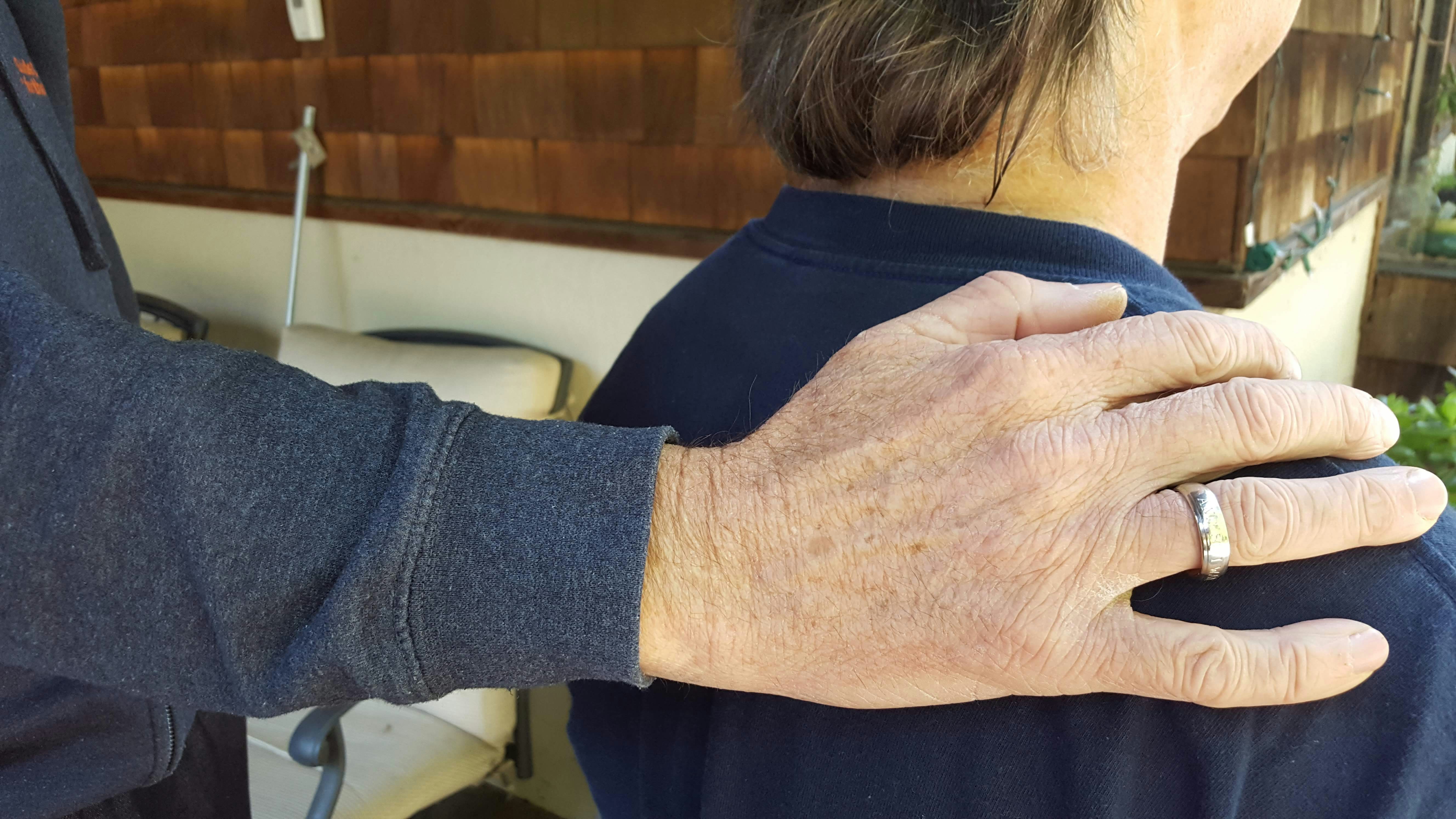 Close-up of therapeutic hands gently holding a shoulder, conveying safety and professional care