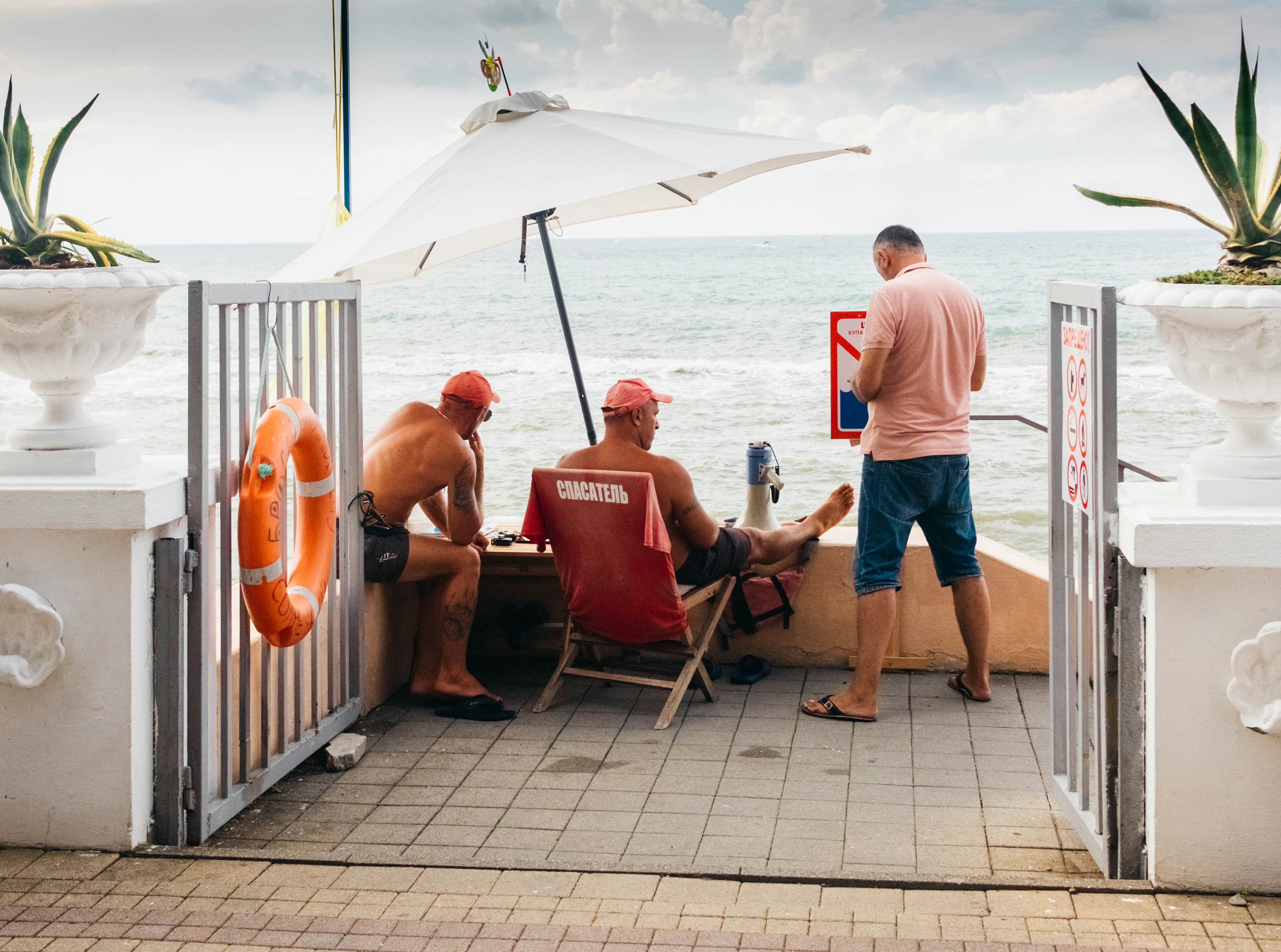 Group of friends drinking beer on a sunny outdoor terrace with motorcycles parked in the background