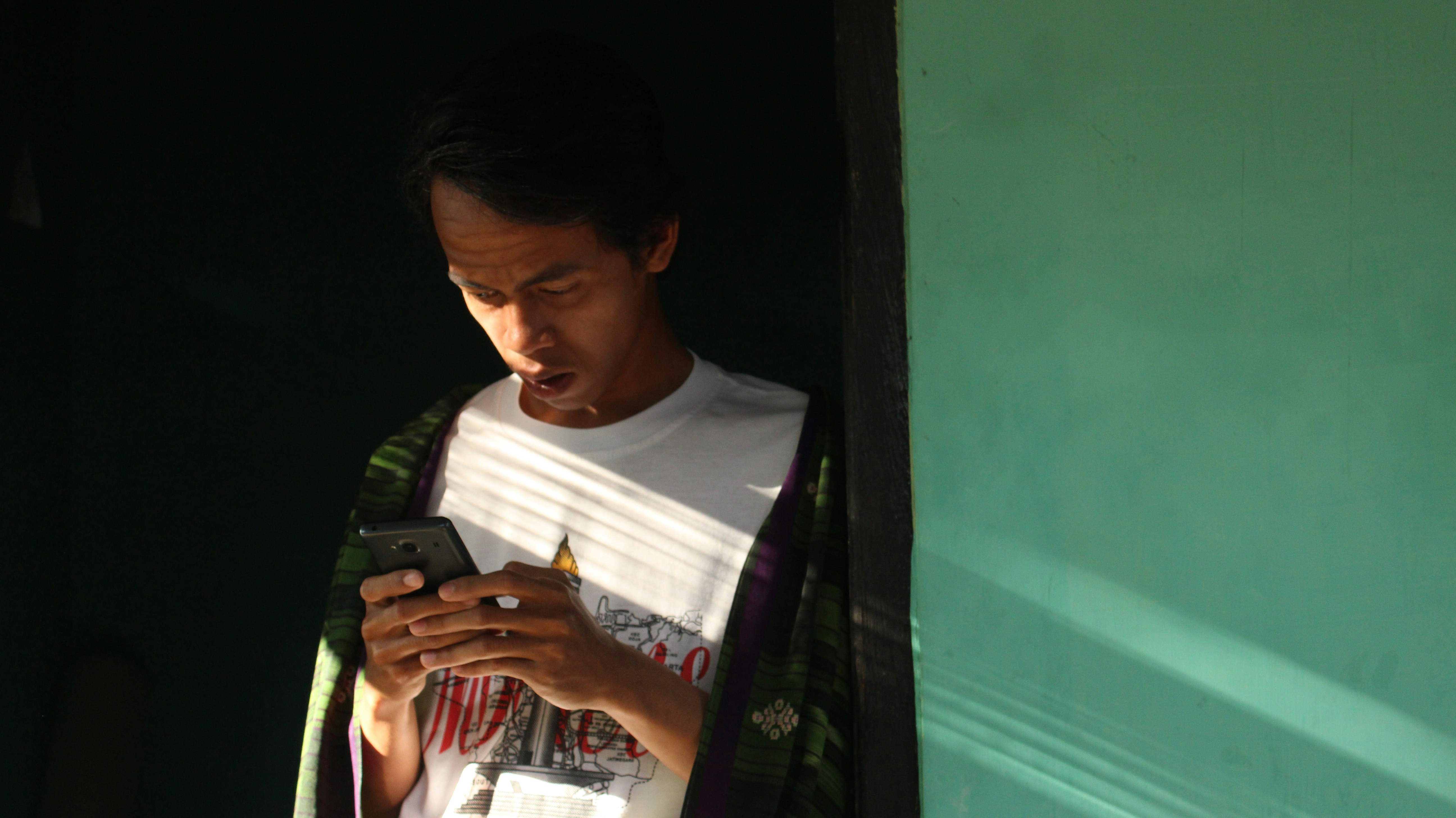Close up photo of a person holding a smartphone scanning a QR code in a dimly light jazz club