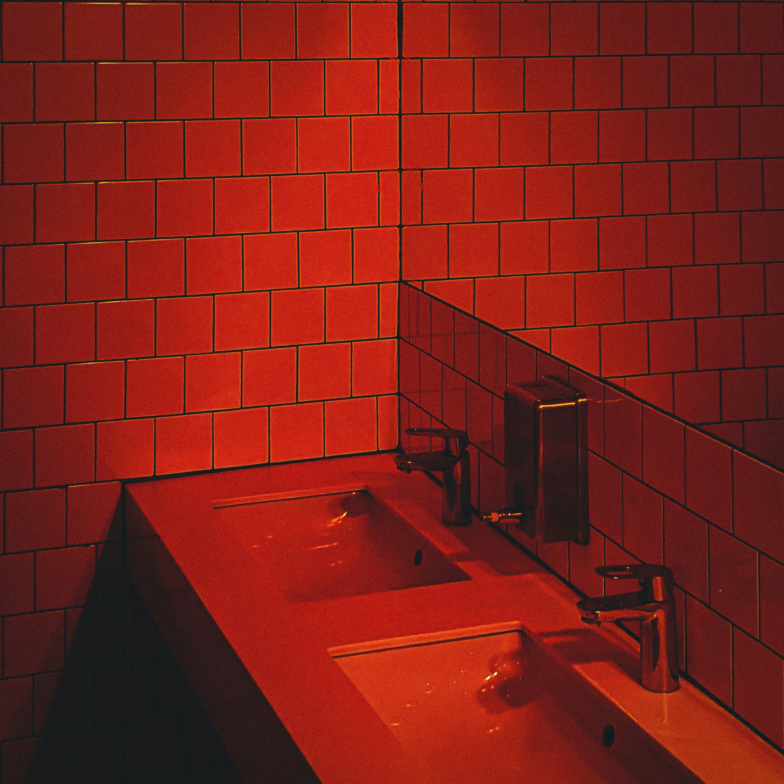 A person using a red rubber plunger on a bathroom sink with focus on the action.