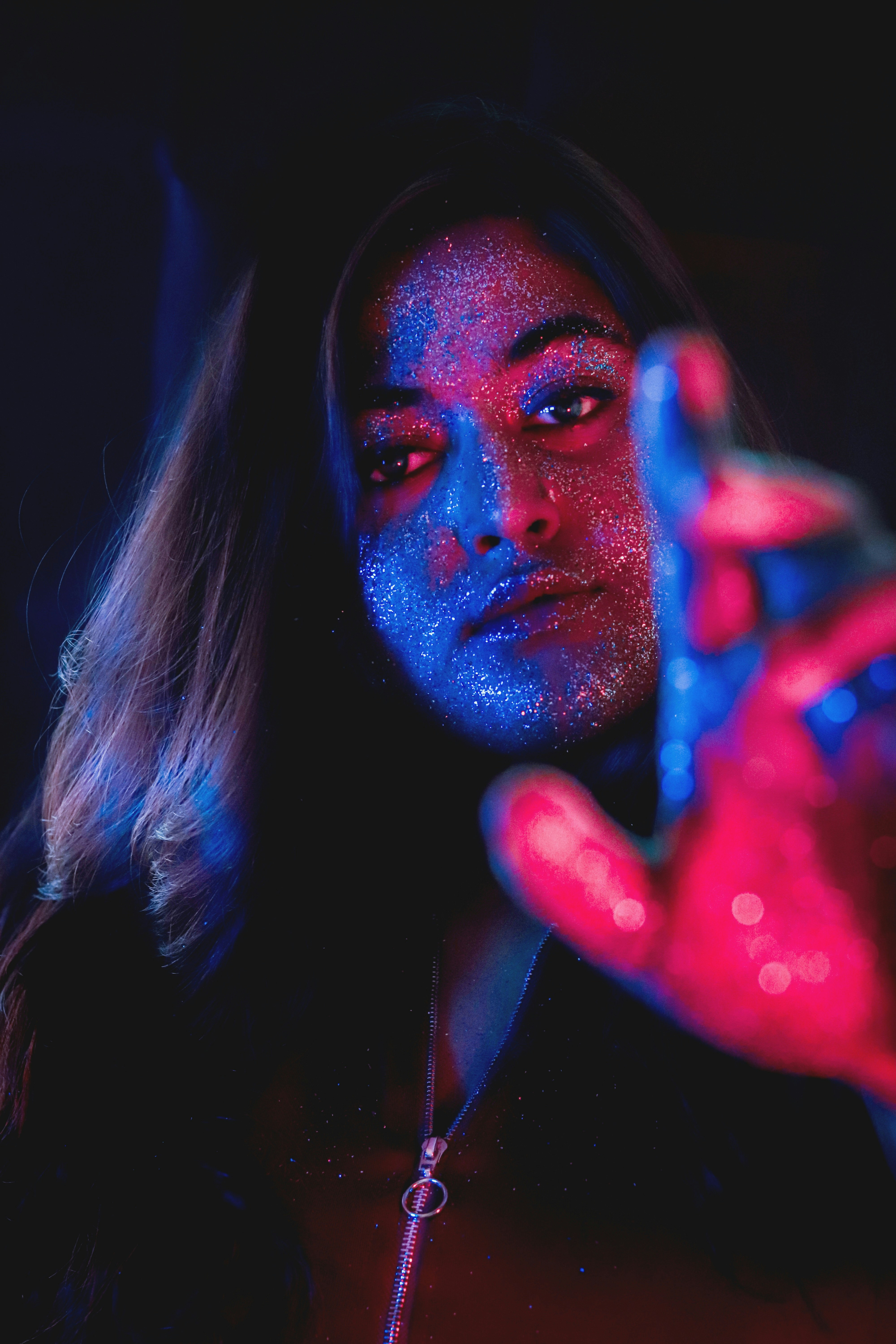 Artistic portrait with colorful gel lighting (red and blue) on a female face, creative makeup, dreamy atmosphere.