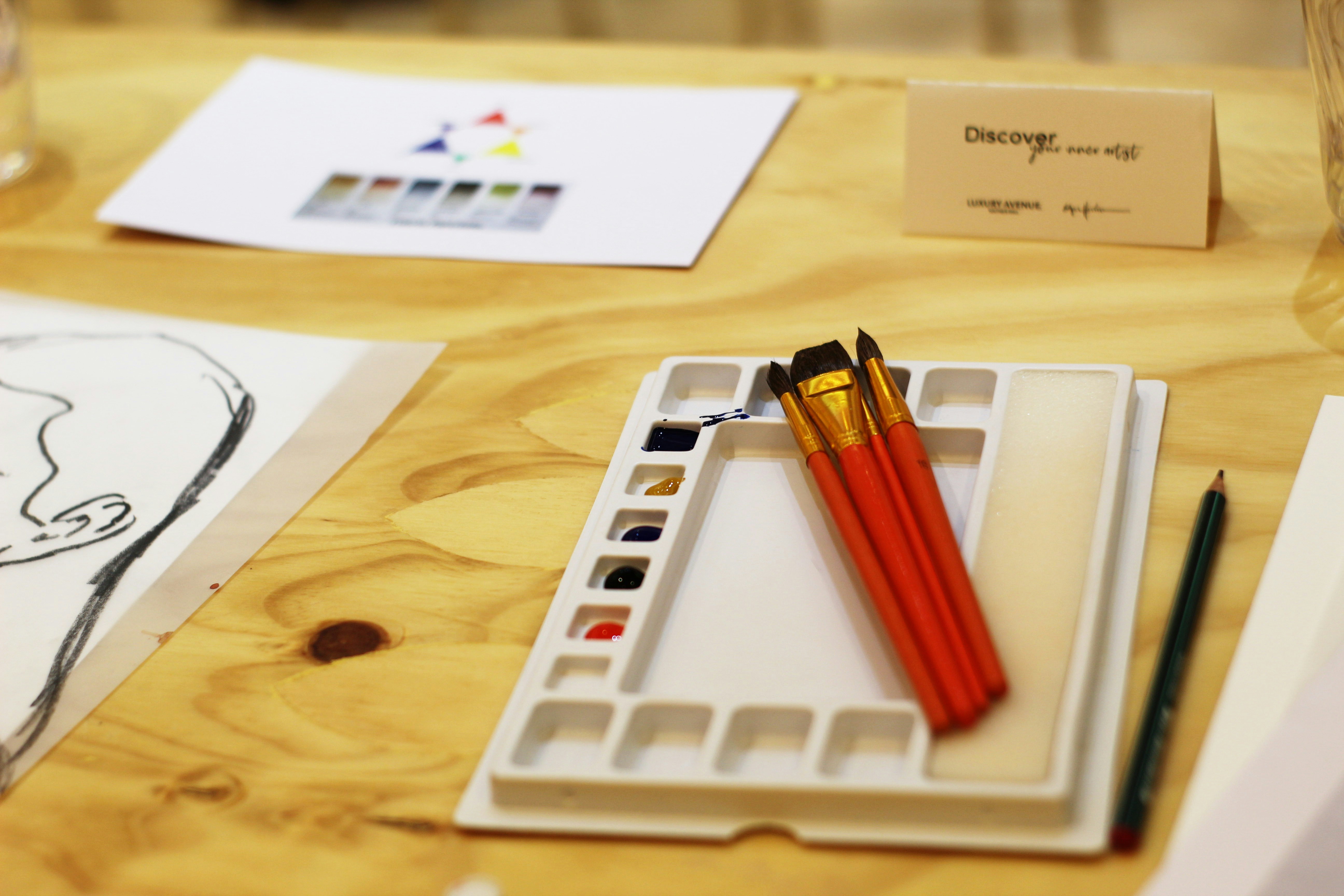 A designer working on a moodboard with fabric samples, color palettes, and sketches of furniture layouts on a wooden table
