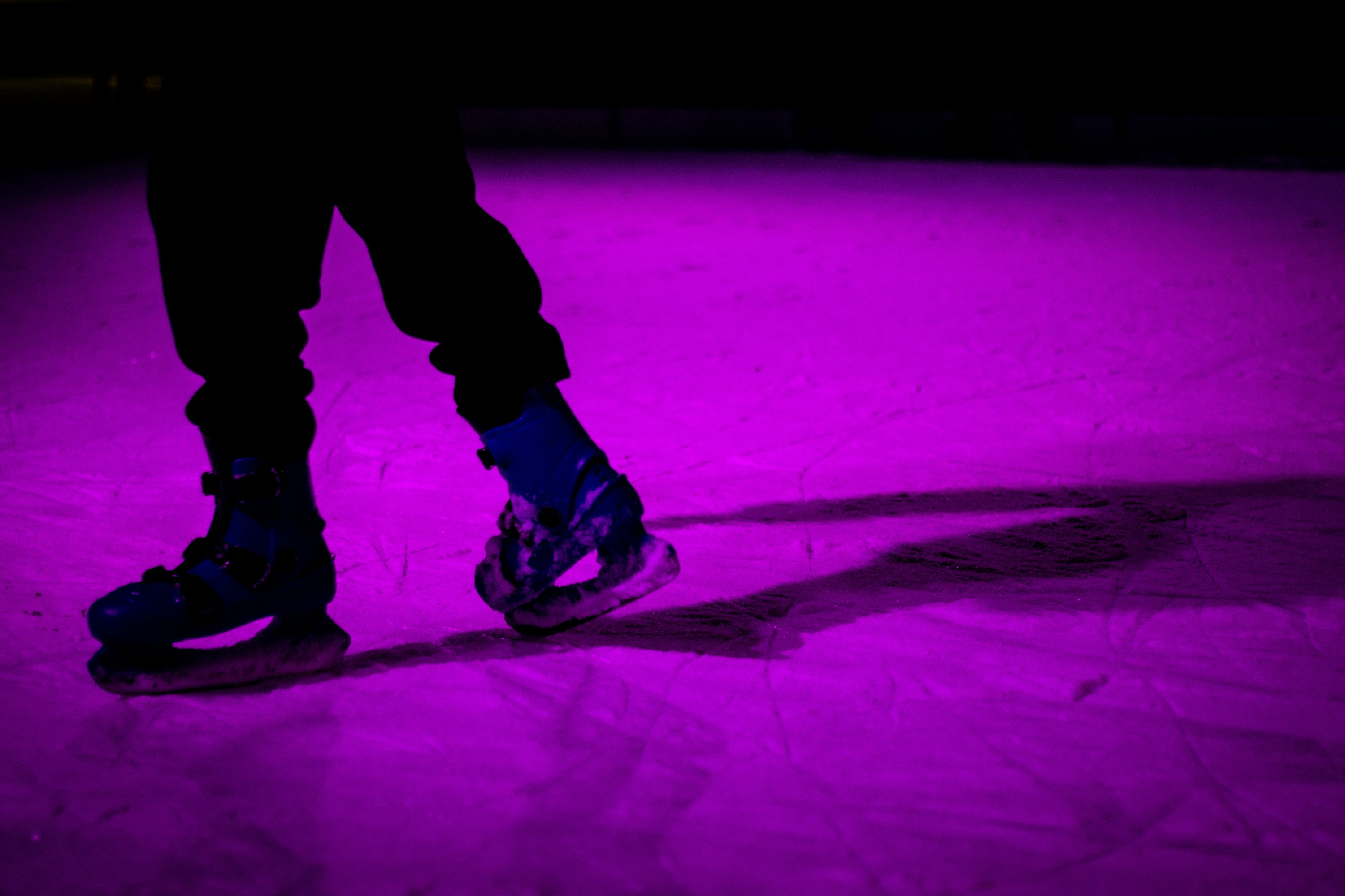 Close up of people ice skating at night wearing glowing silent disco headphones