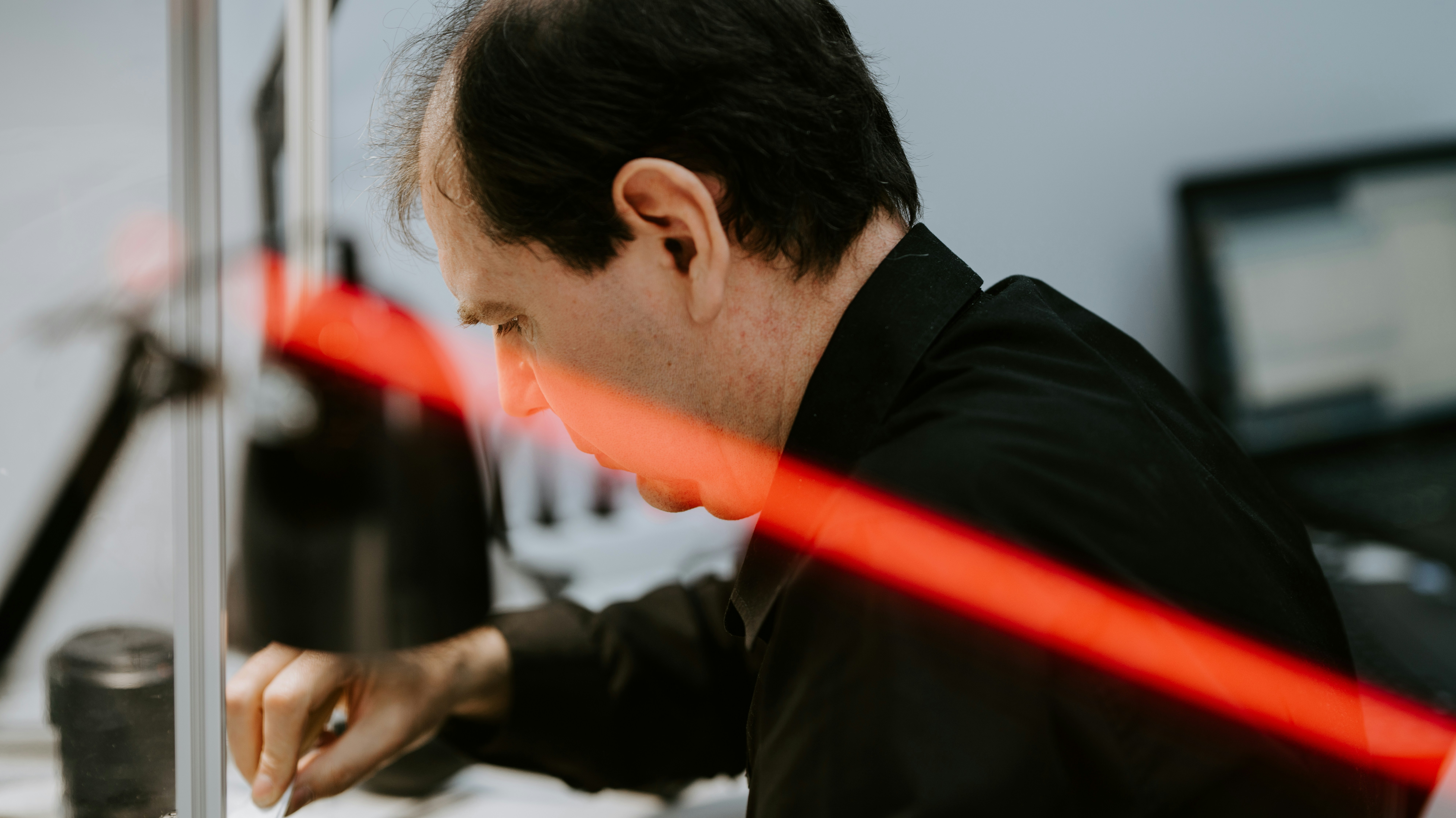 Technicien professionnel utilisant un niveau laser pour installer un store sur mesure dans une baie vitrée complexe