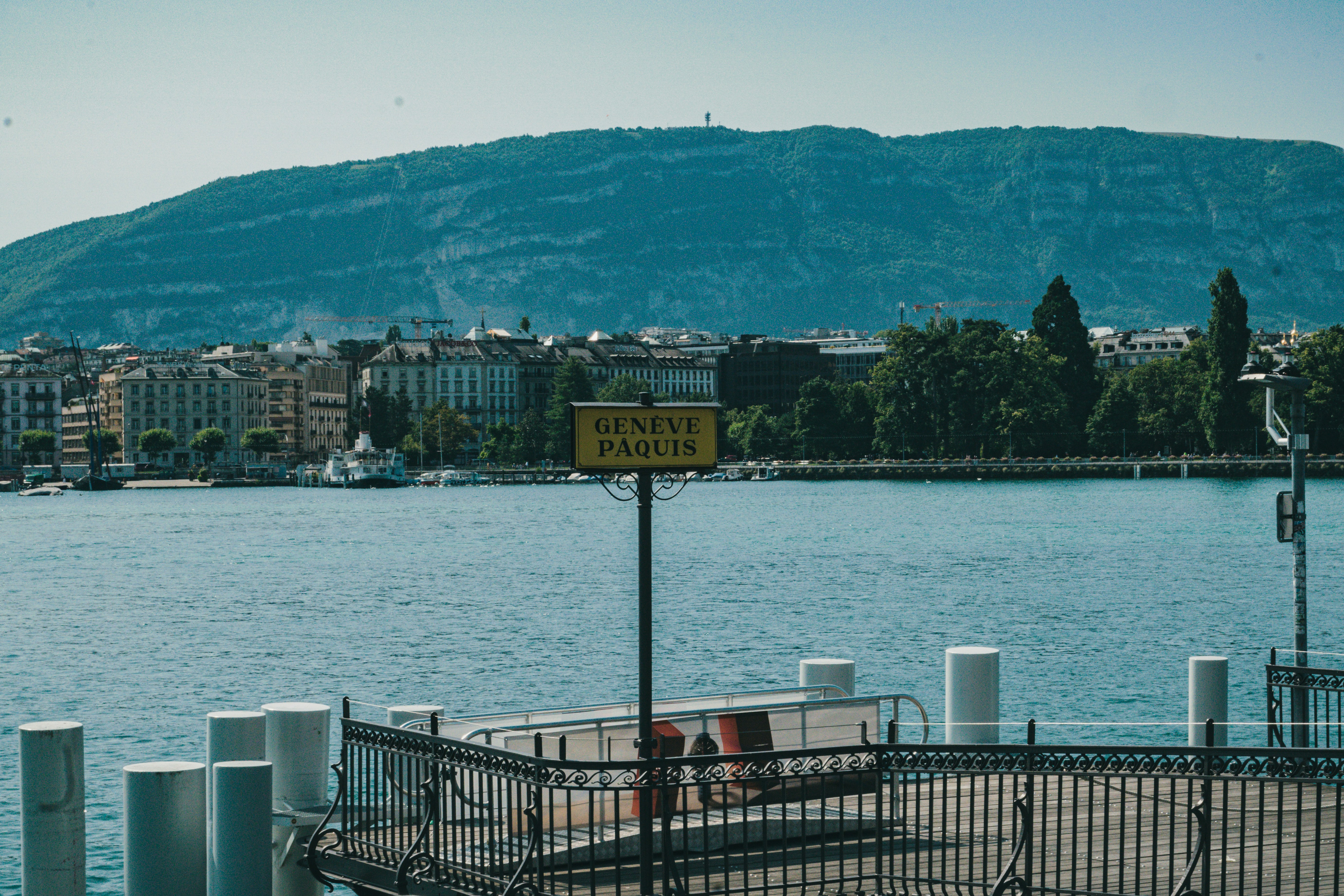 Man running on a treadmill in a modern gym with a view of Lake Geneva.