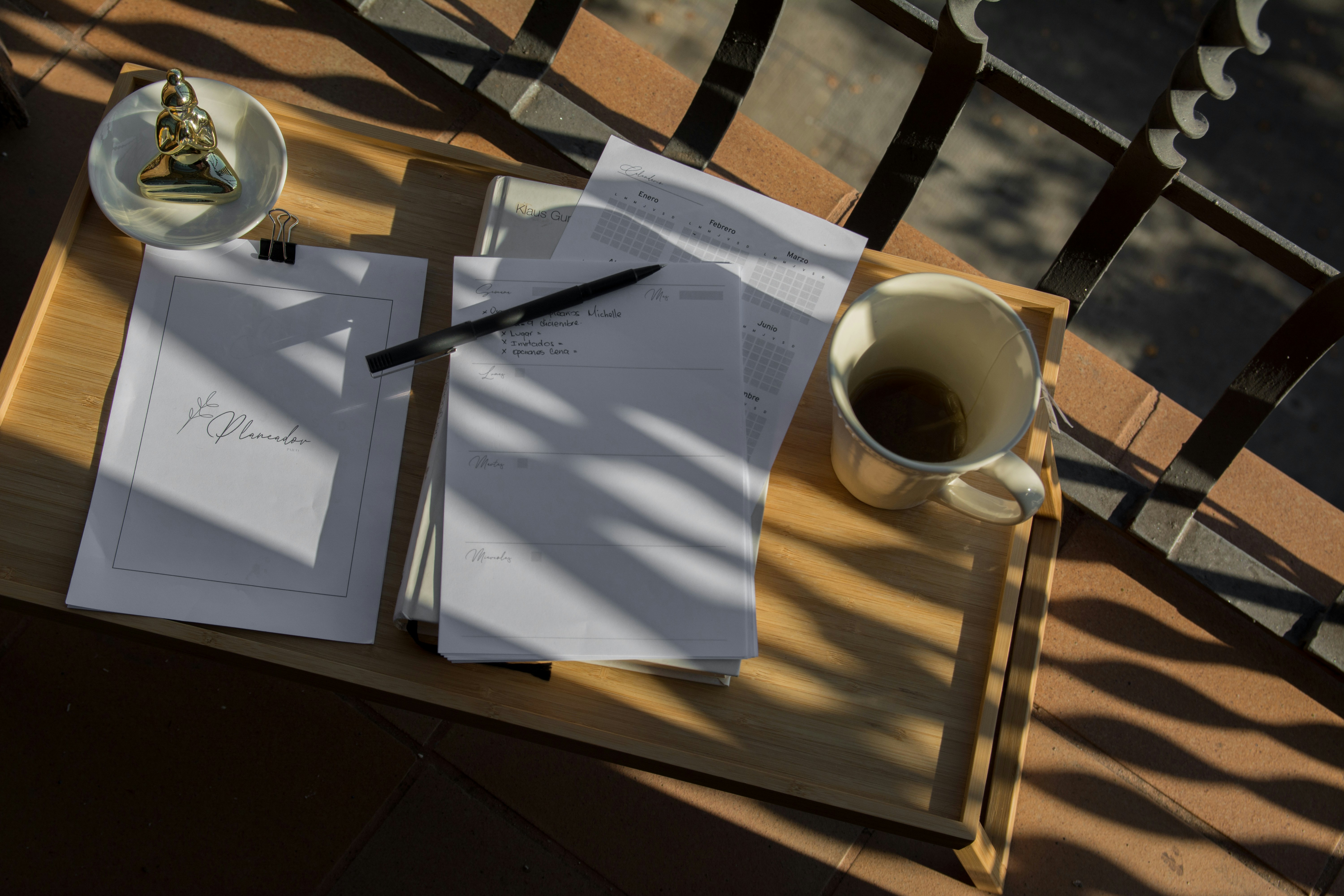 Close up of a notebook and a pen on a wooden desk with a serene background evoking end of work day