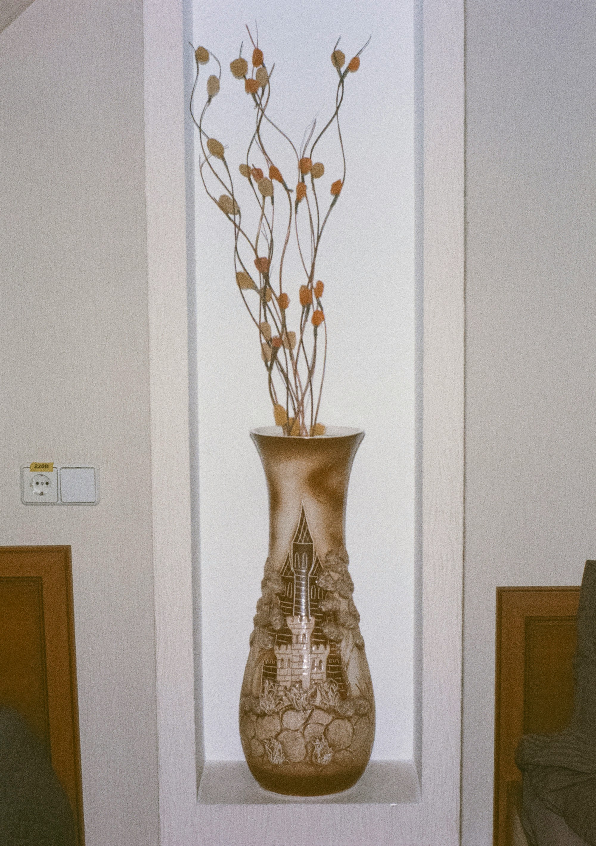 Détail d'un vase en céramique artisanale avec des fleurs séchées sur une nappe en lin