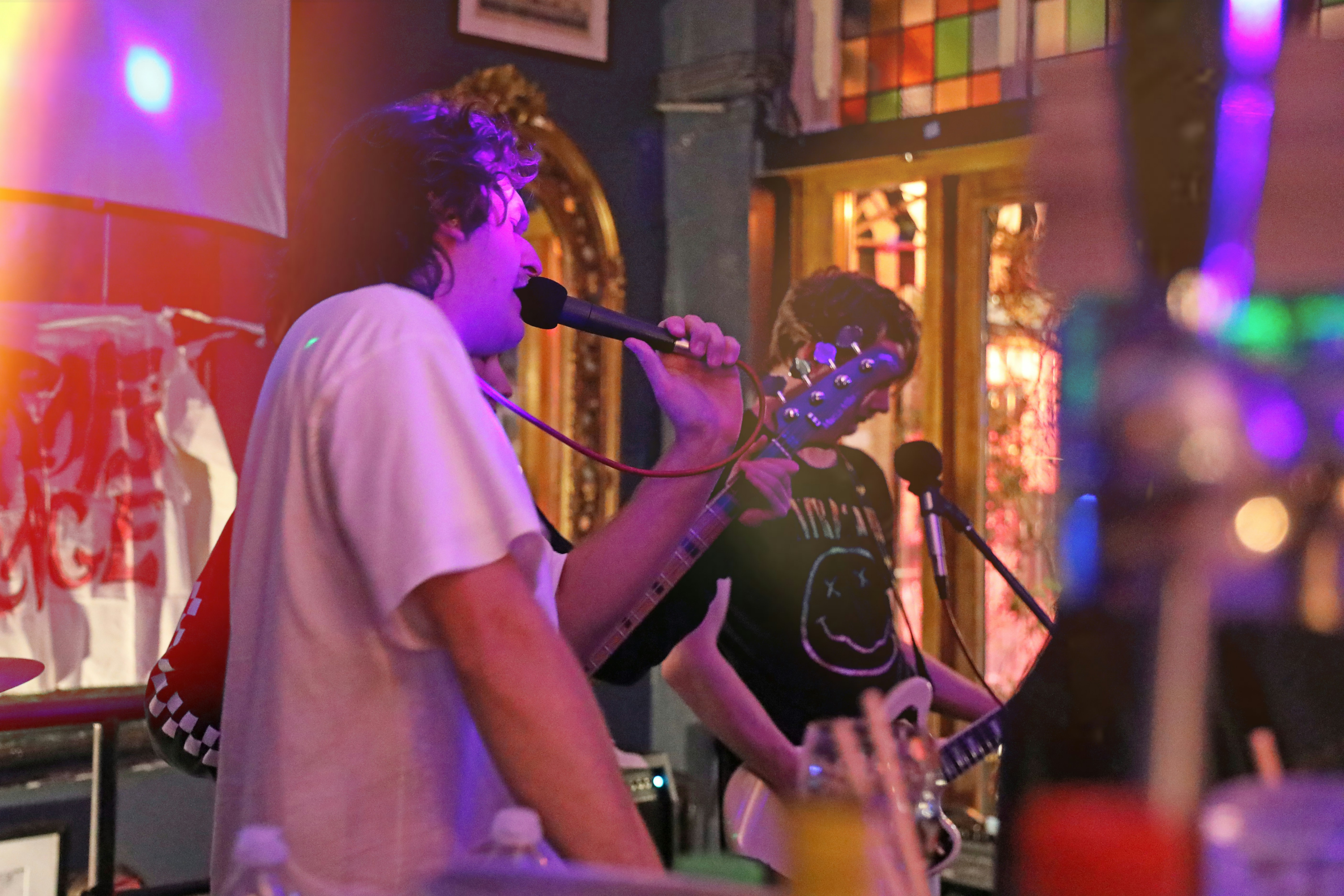 Close up of a rock band playing live music in a bar with guitar and microphone, moody lighting, energetic atmosphere