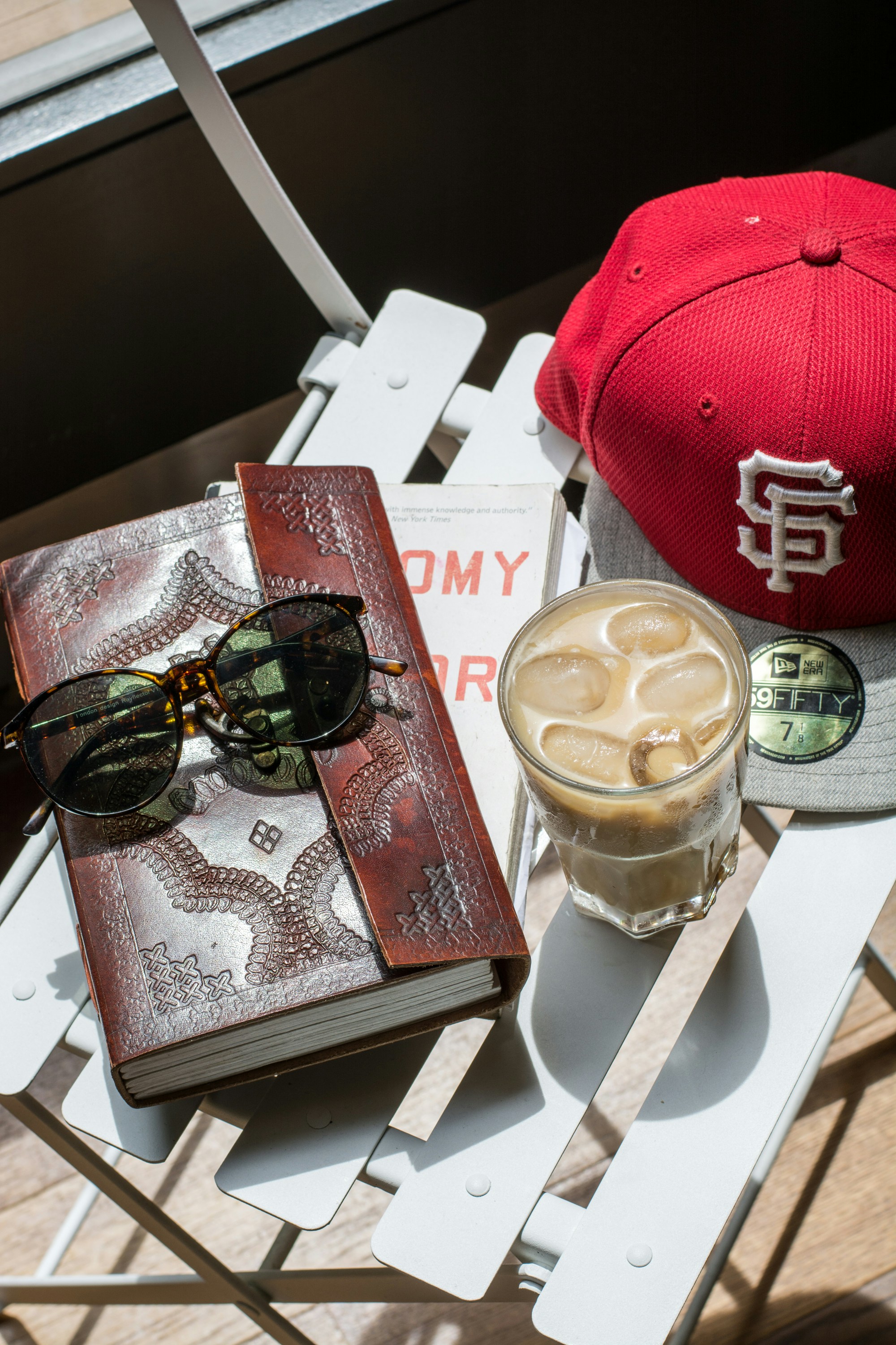 A cozy balcony with books and coffee, shaded by a textured sun blind