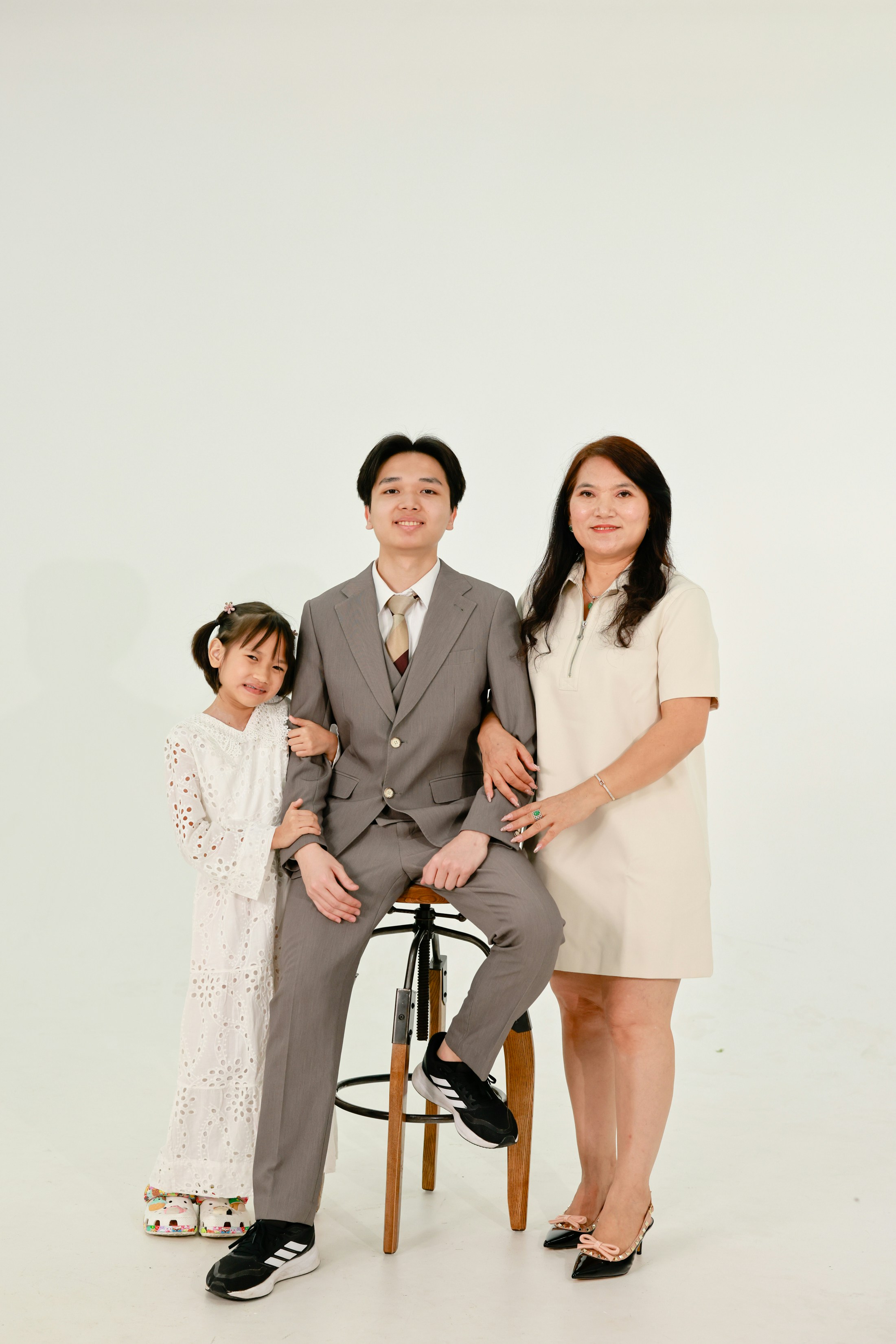 Professional photographer showing previews on a camera screen to a happy family in a studio setting.
