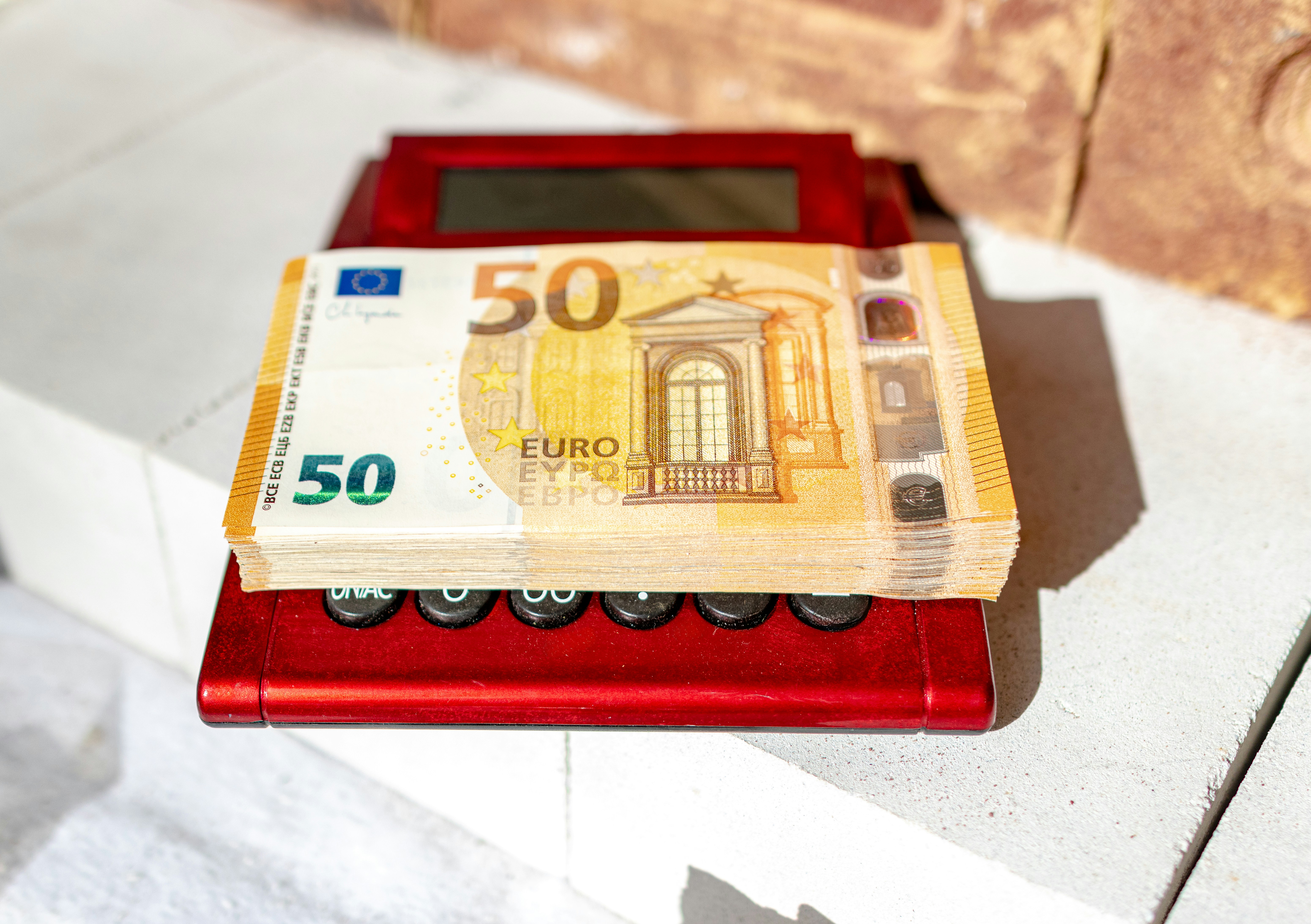 Close up photo of a calculator and euro coins on a wooden table symbolizing savings