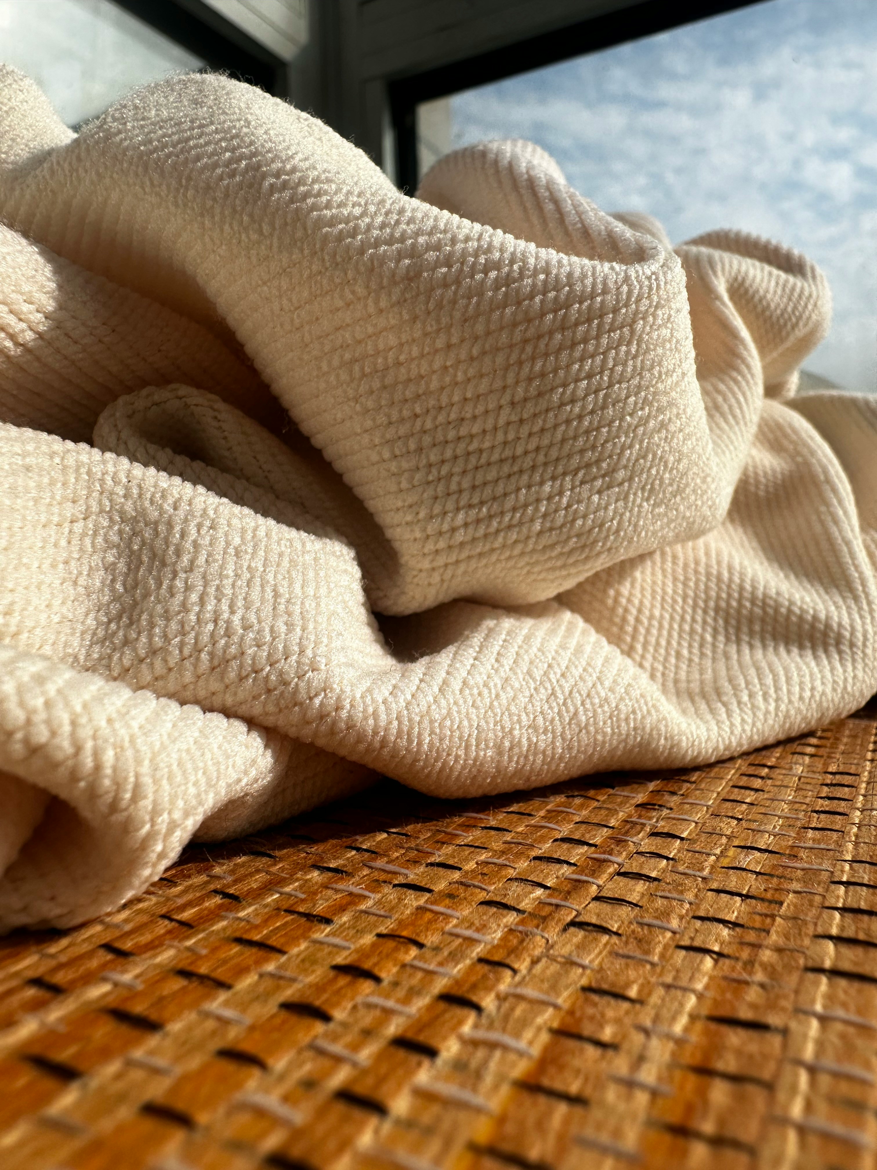 Flat lay of clothing grouping showing texture mixing: a chunky knit cardigan, a smooth silk camisole, and denim fabric together.