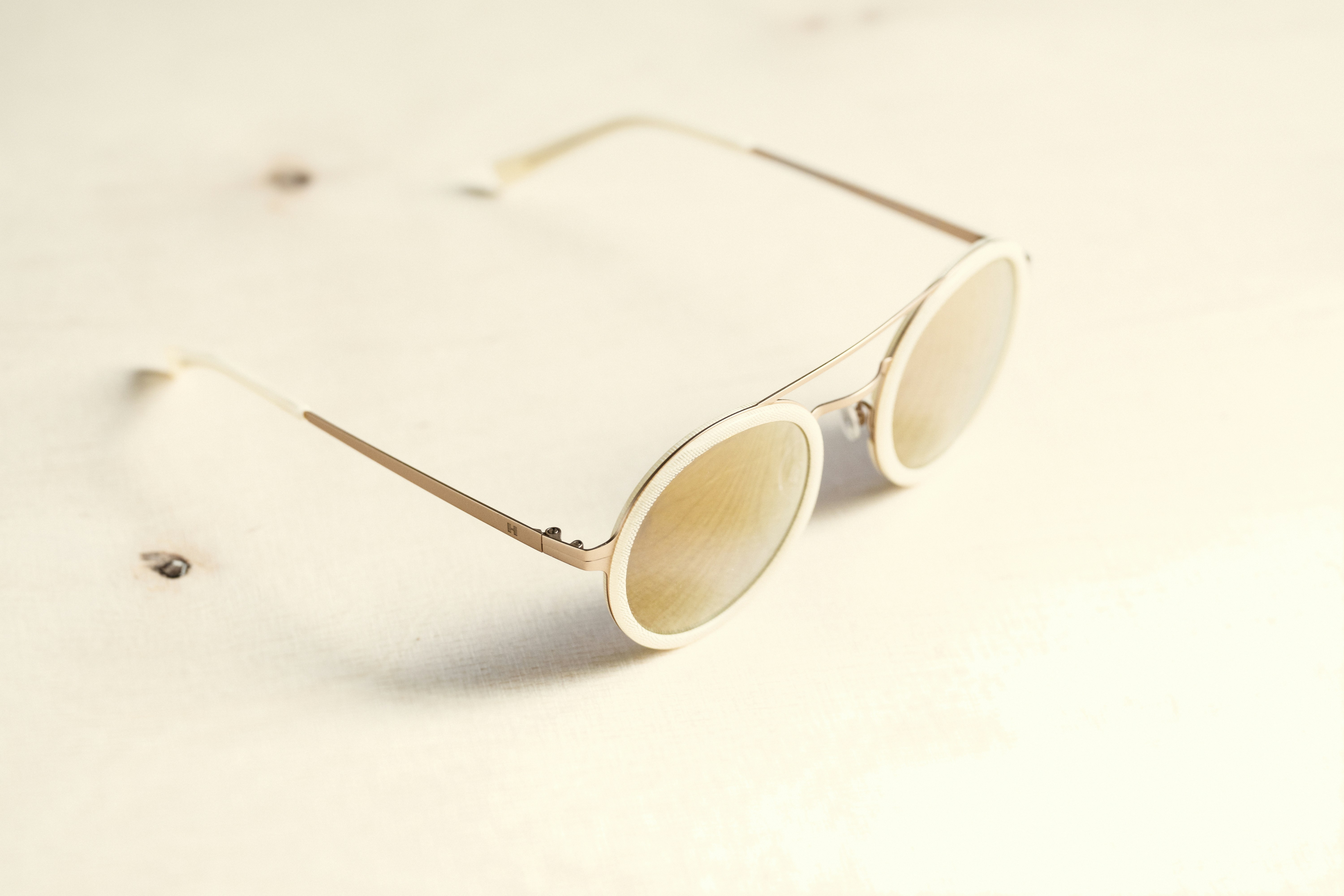 Close up of gold layered necklaces and sunglasses on a woman wearing a white cotton tee.