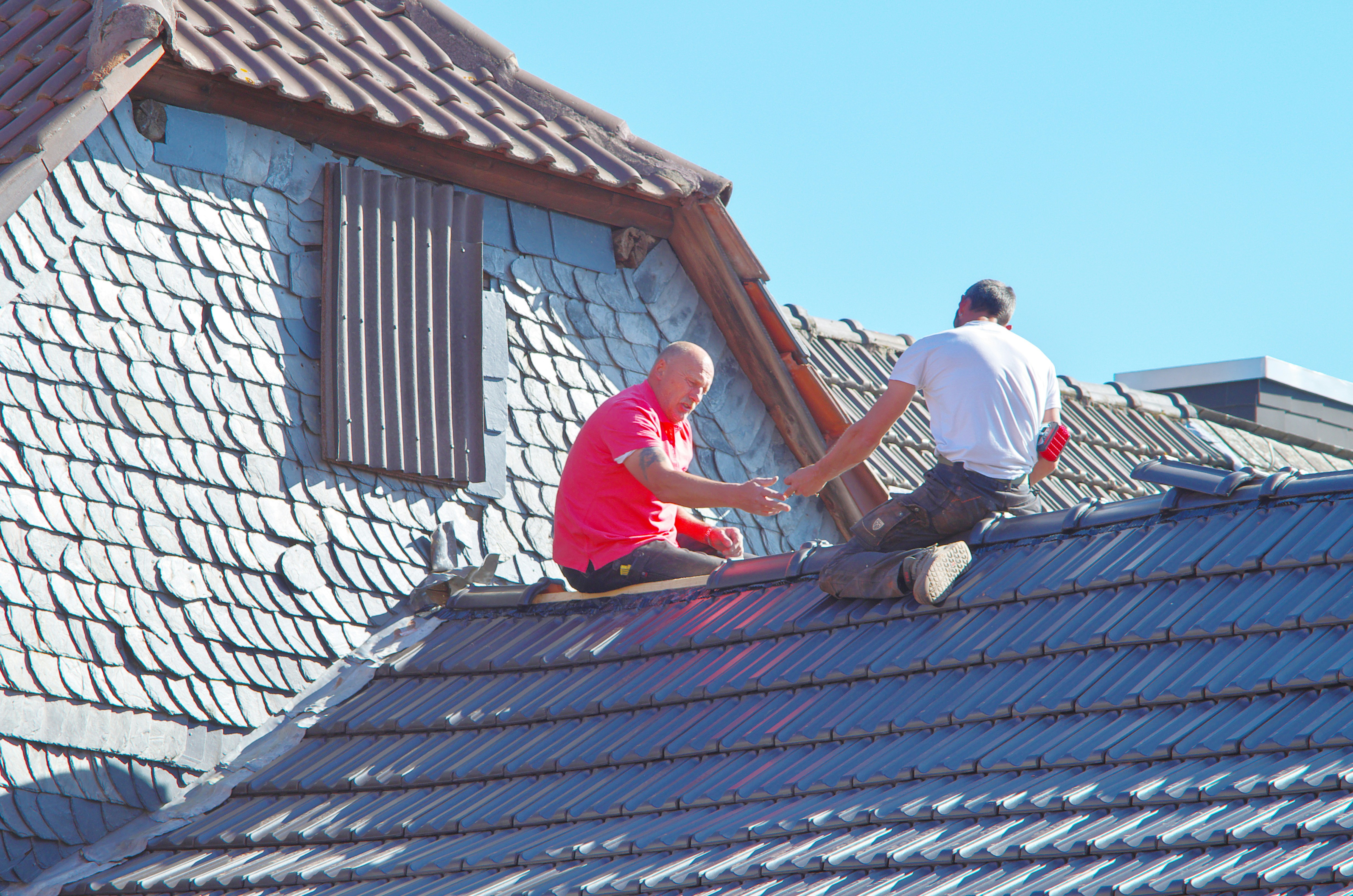 A professional roofer inspecting a roof with tablet in hand taking notes