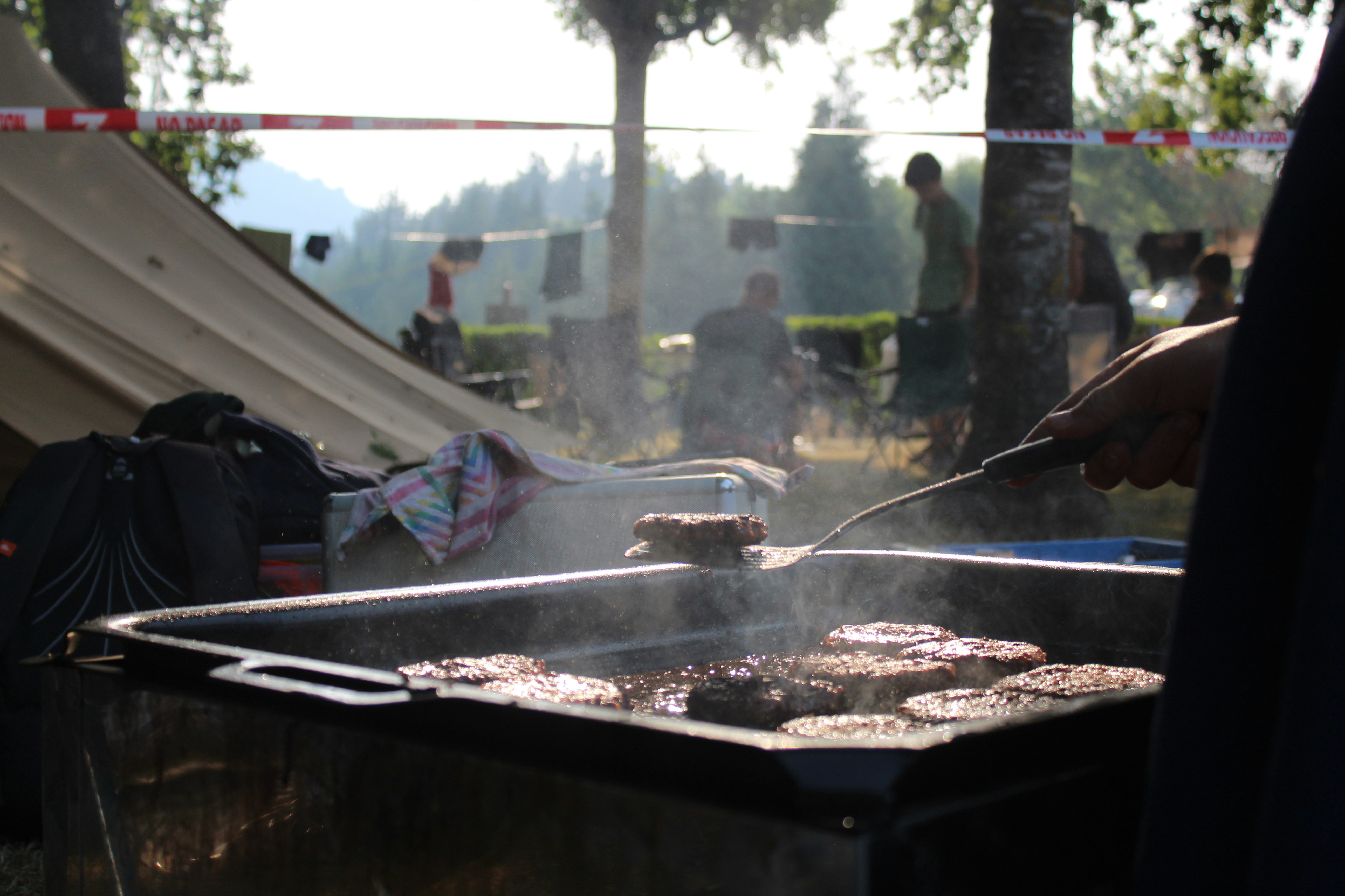 Grillades sur un barbecue extérieur lors d'un événement motard, ambiance conviviale et fumée appetissante