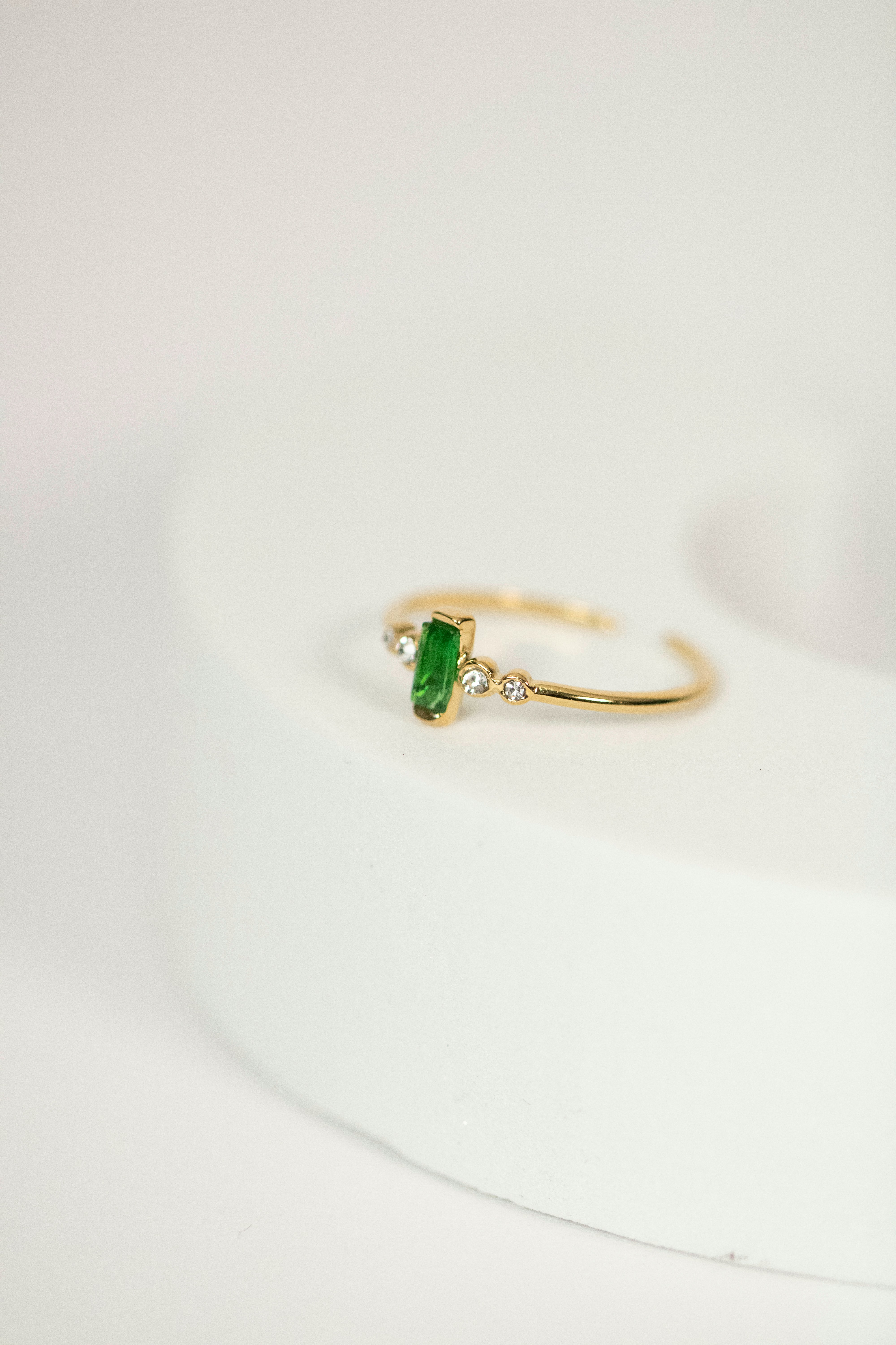 An elegant artisanal ring with a green sapphire on a silk fabric background