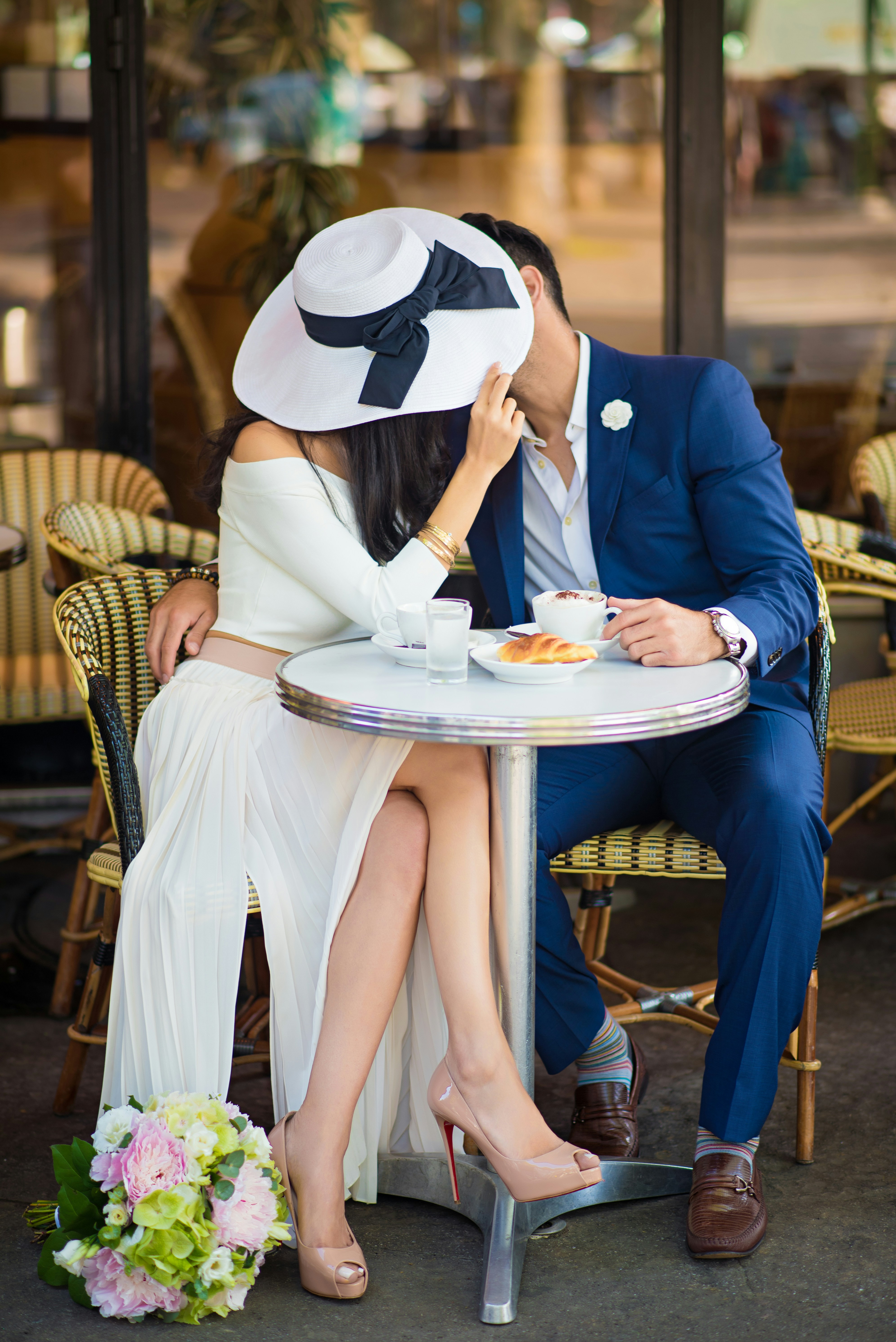Couple holding hands looking at an engagement ring in a romantic Parisian cafe setting