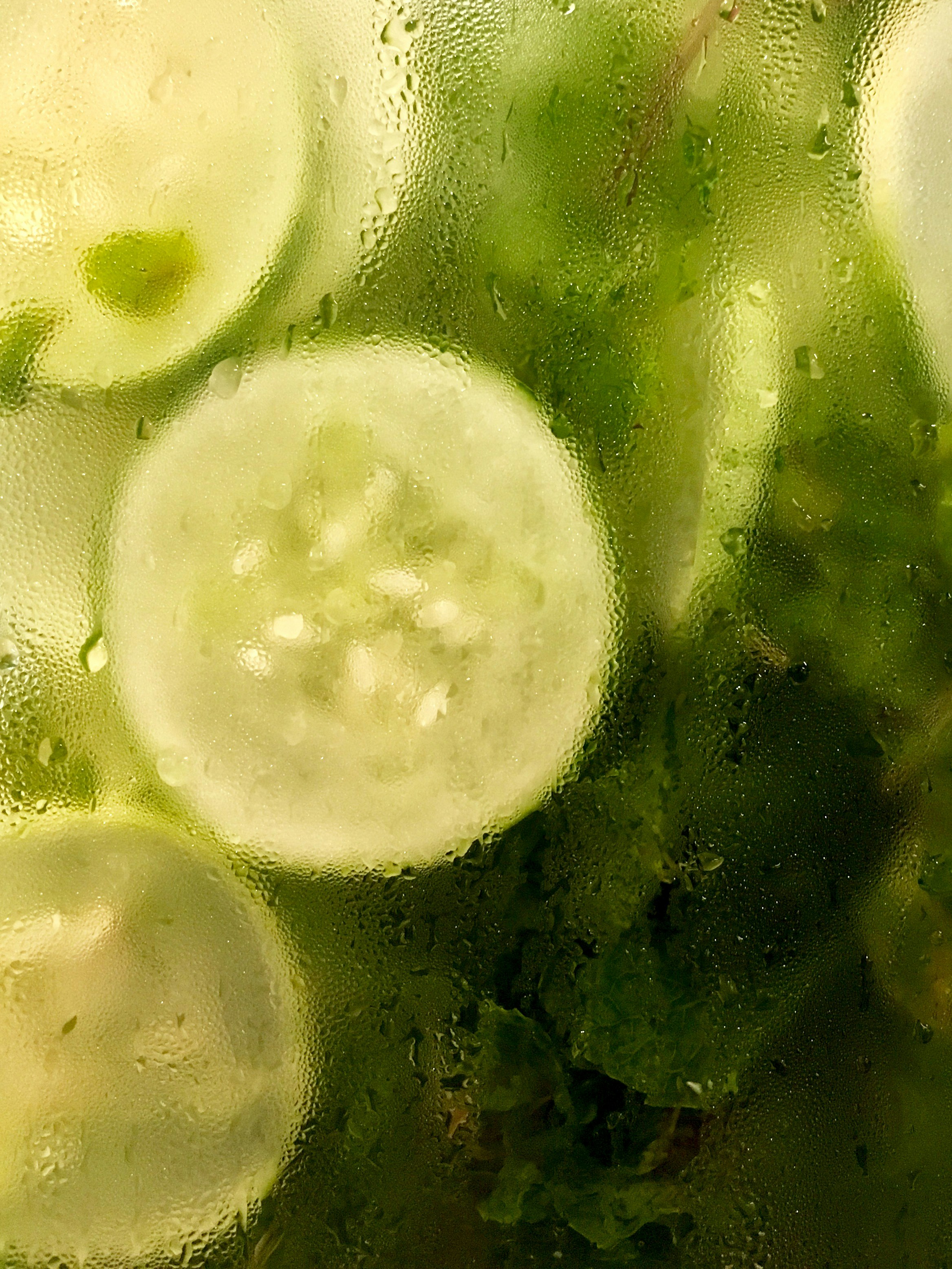 Close up shot of a spoon pouring light fresh cream over fresh cucumber salad with dill