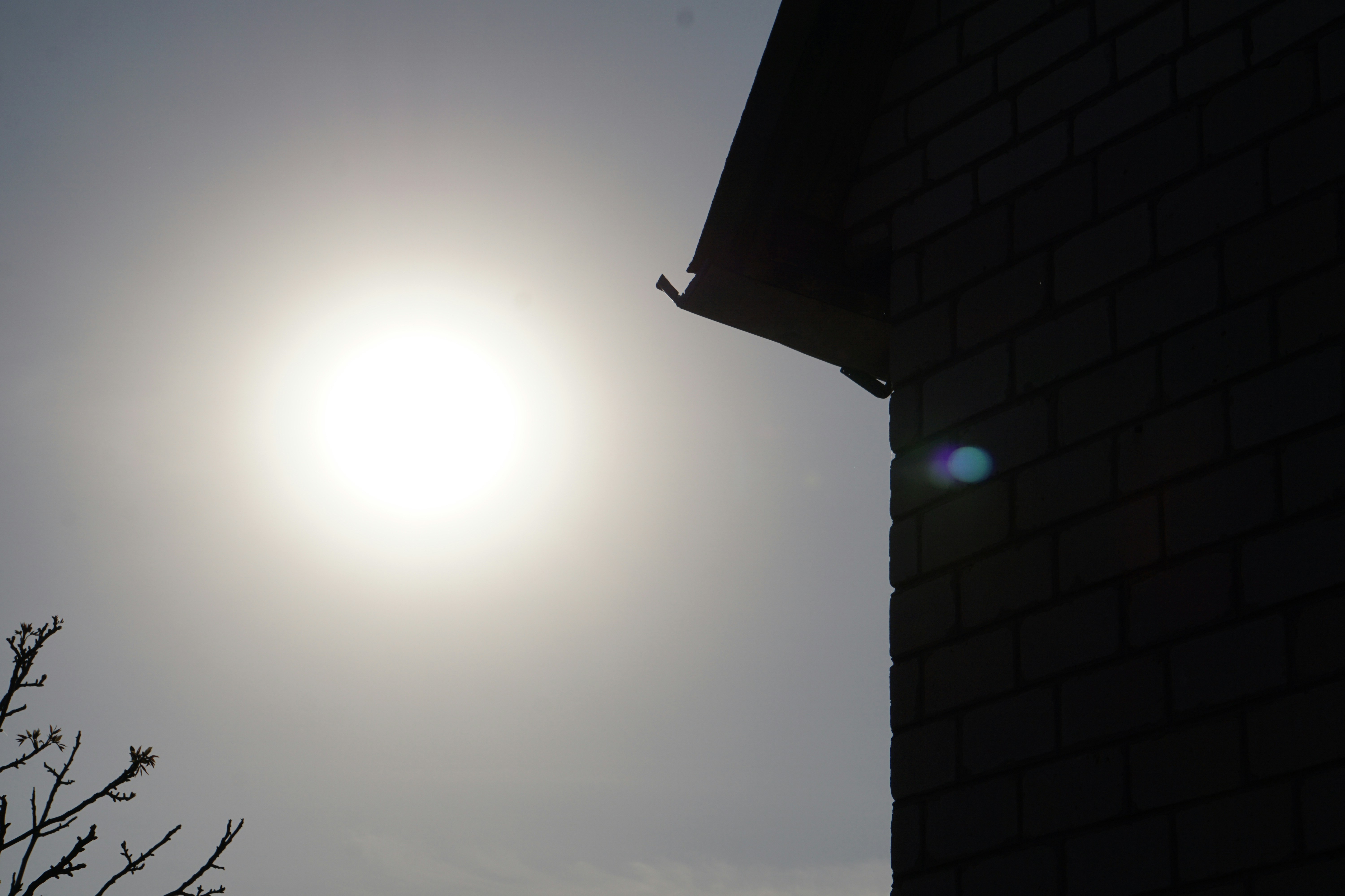 Close up of a hand holding a Somfy remote control pointing at a terrace awning