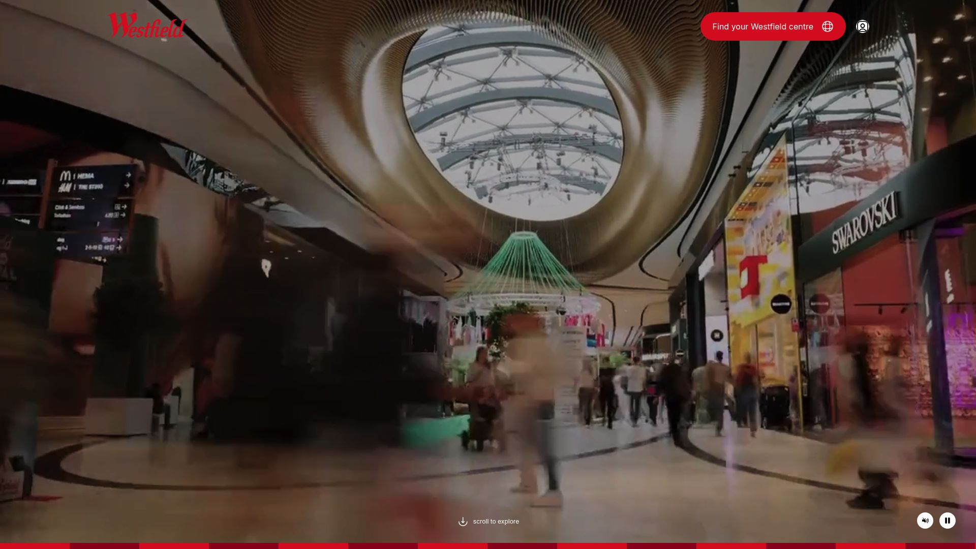 Un hall d'entrée de centre commercial moderne et lumineux, avec des panneaux directionnels suspendus élégants et un grand totem numérique affichant le plan du centre. L'ambiance est accueillante et épurée.