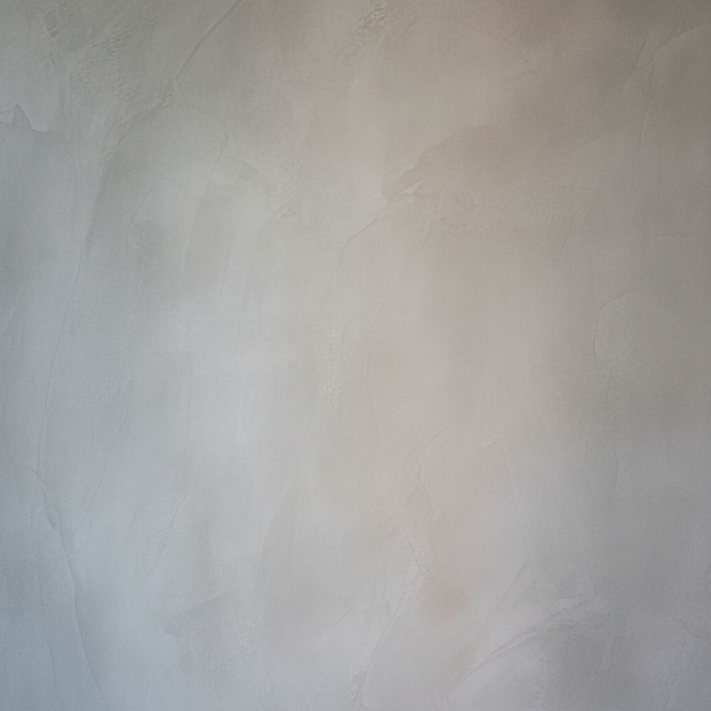 Un gros plan sur la texture subtilement texturée et lisse d'un mur en béton ciré, montrant les légères variations de couleur qui lui donnent son caractère unique.