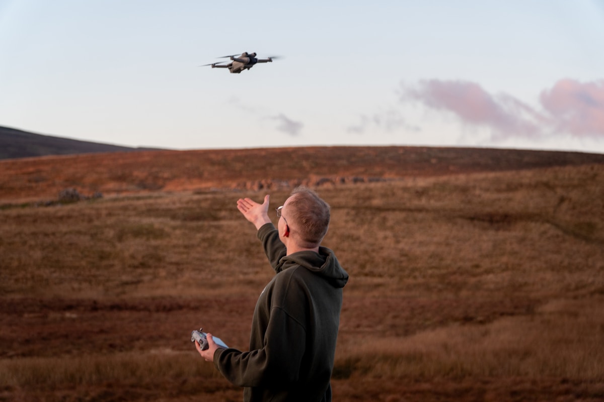 Homme pilotant un drone dans un paysage désertique.