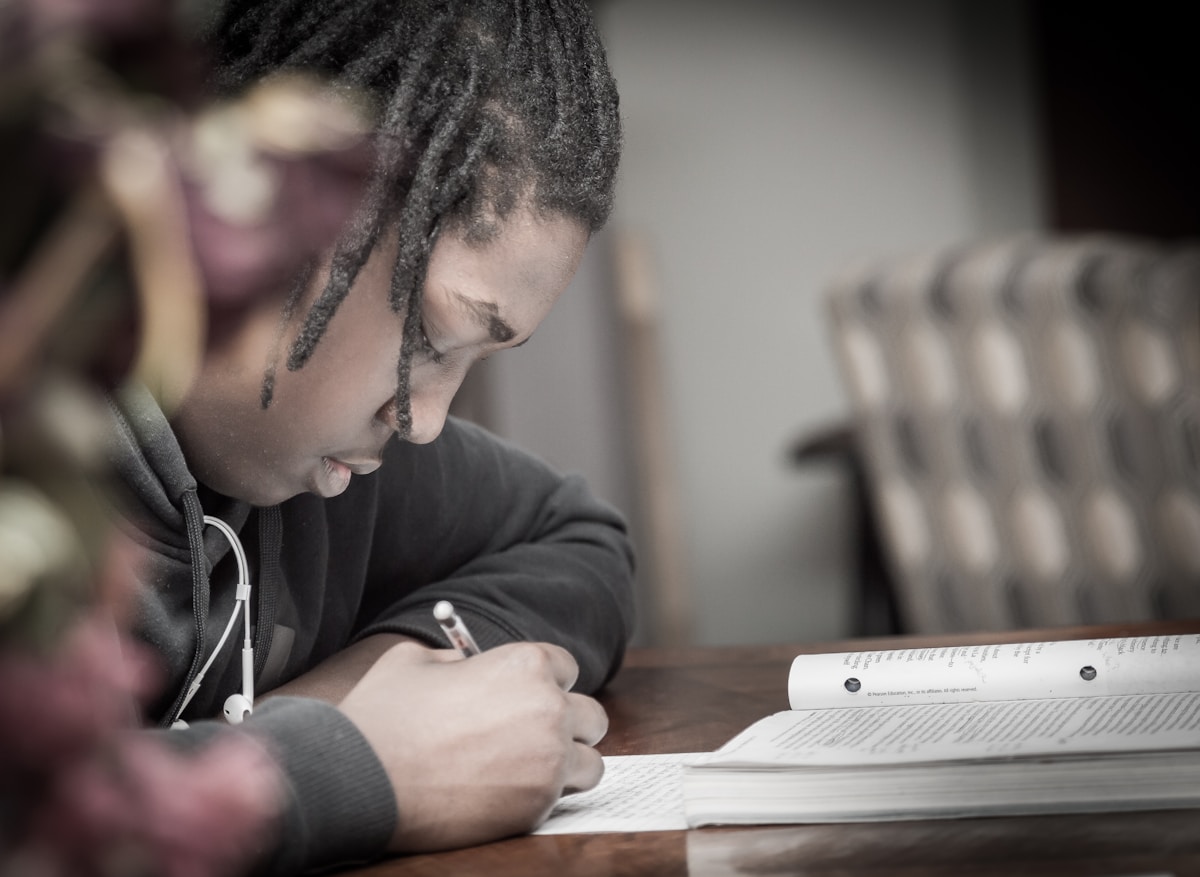 Jeune homme concentré, étudiant, écrivant dans un cahier.