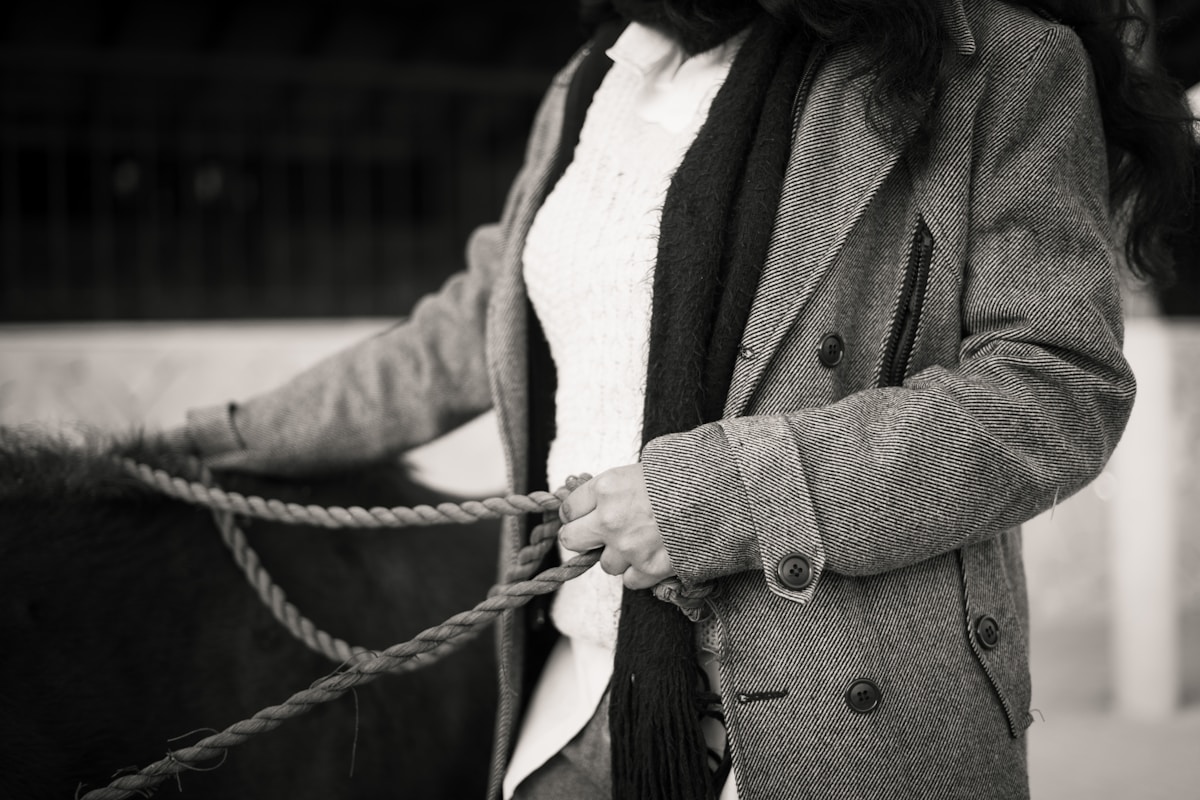 Homme en manteau gris tenant une corde.