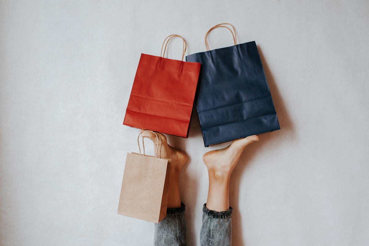 Three shopping bags held by feet against wall