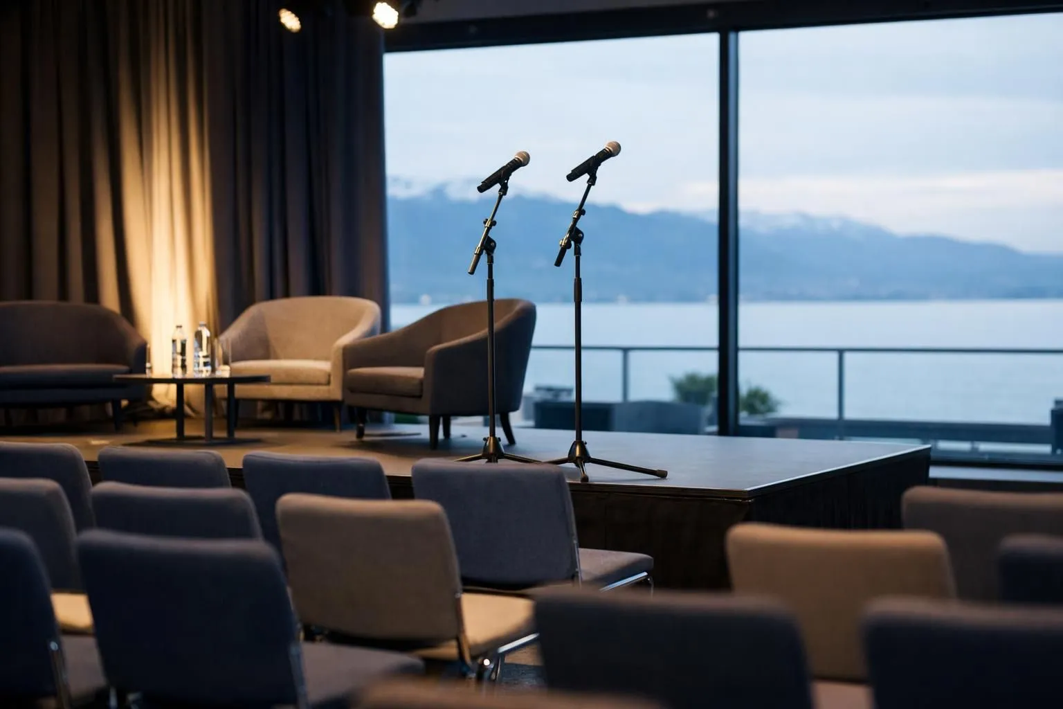 Modern event venue in Lausanne with professional stage setup, ambient lighting, and elegant seating arrangement prepared for corporate gathering, lakeside windows visible in background