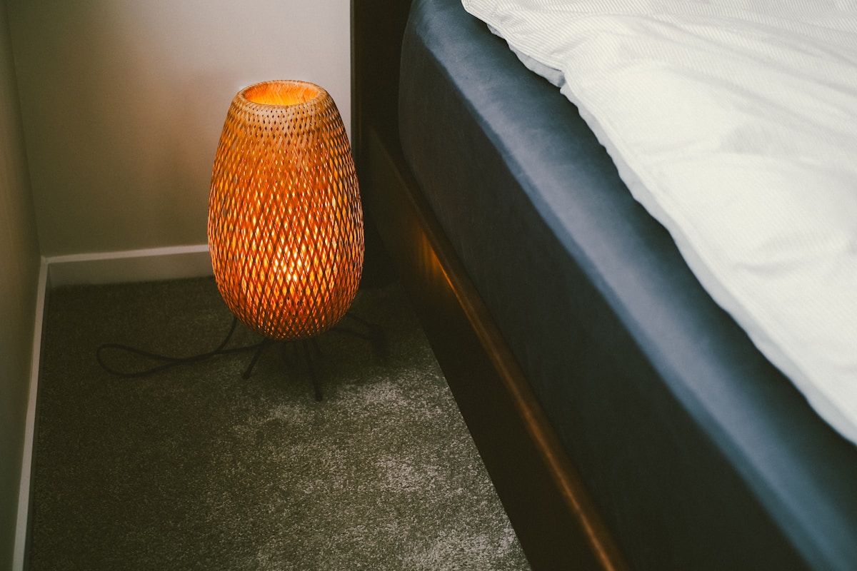 A bedside lamp illuminates a bedroom corner.