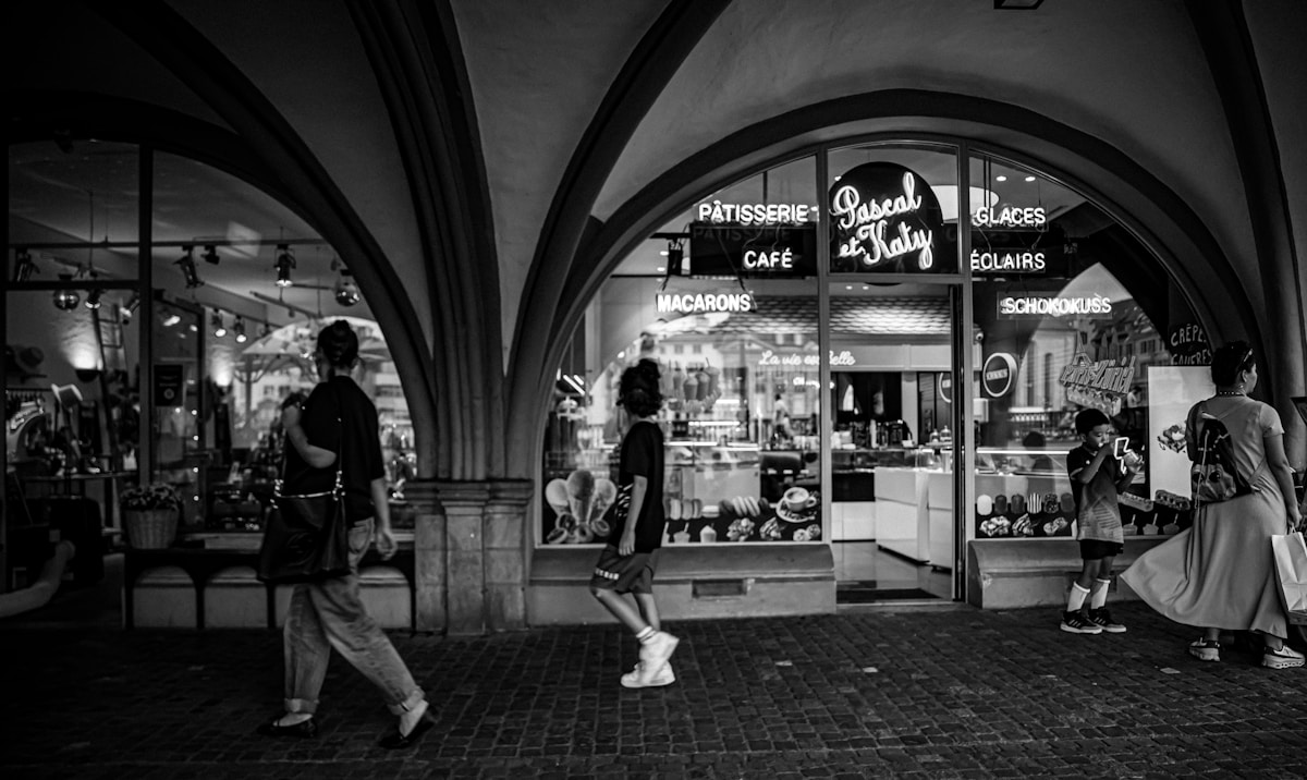a black and white photo of people walking in front of a store