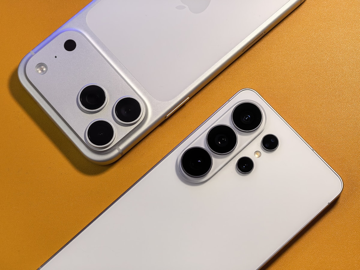 Deux smartphones Apple iPhone avec caméras arrière sophistiquées sur fond orange.