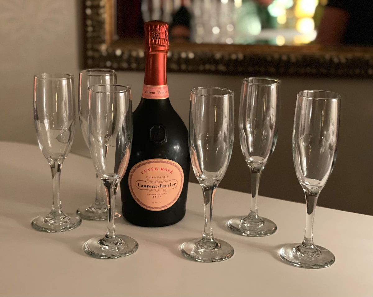 Bouteille de champagne rosé Laurent-Perrier et verres à champagne sur une table.