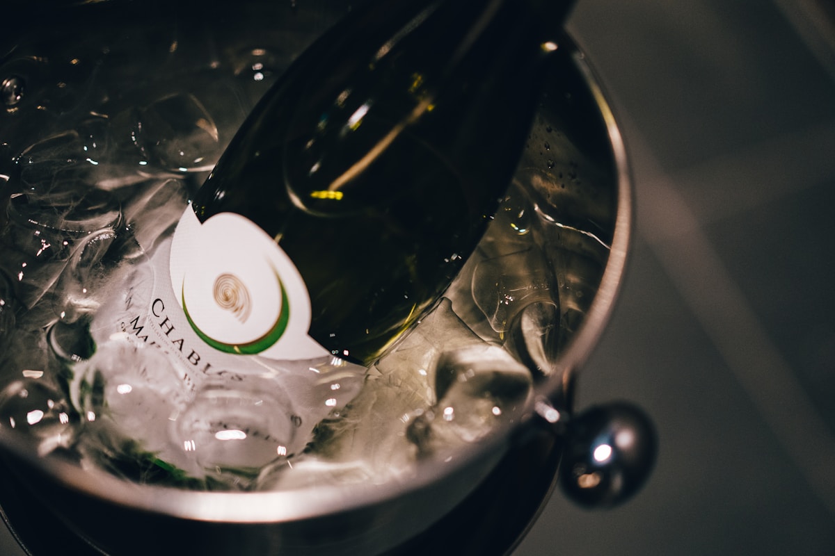 Bouteille de vin rouge et verre de vin blanc sur fond sombre.