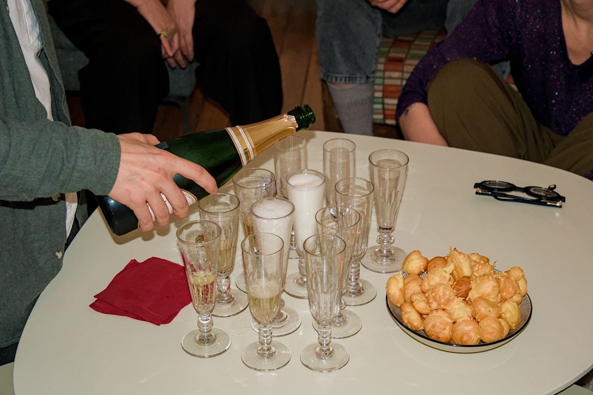 Verres de champagne, beignets et mains versant le champagne.