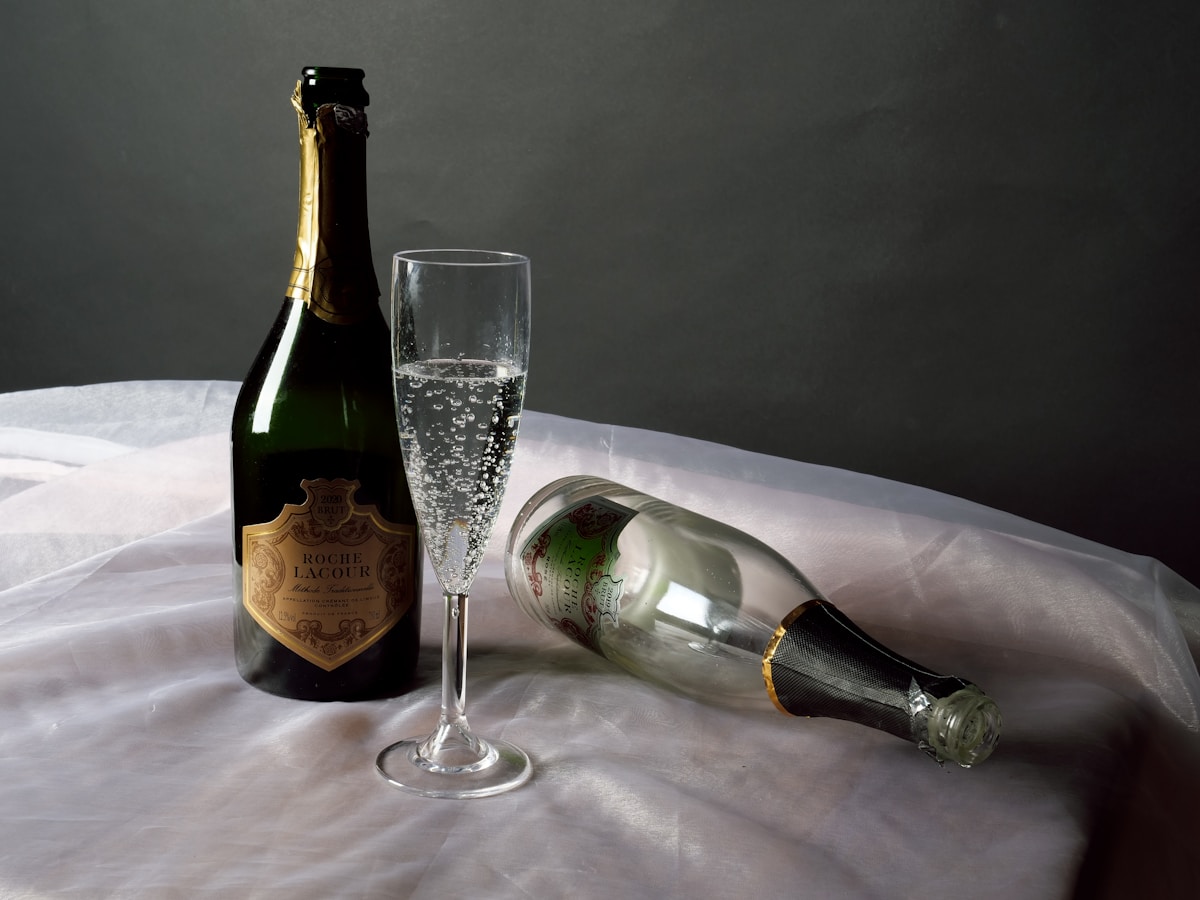 Bouteille de champagne Roche Lacour, verre rempli de bulles, fond sombre.