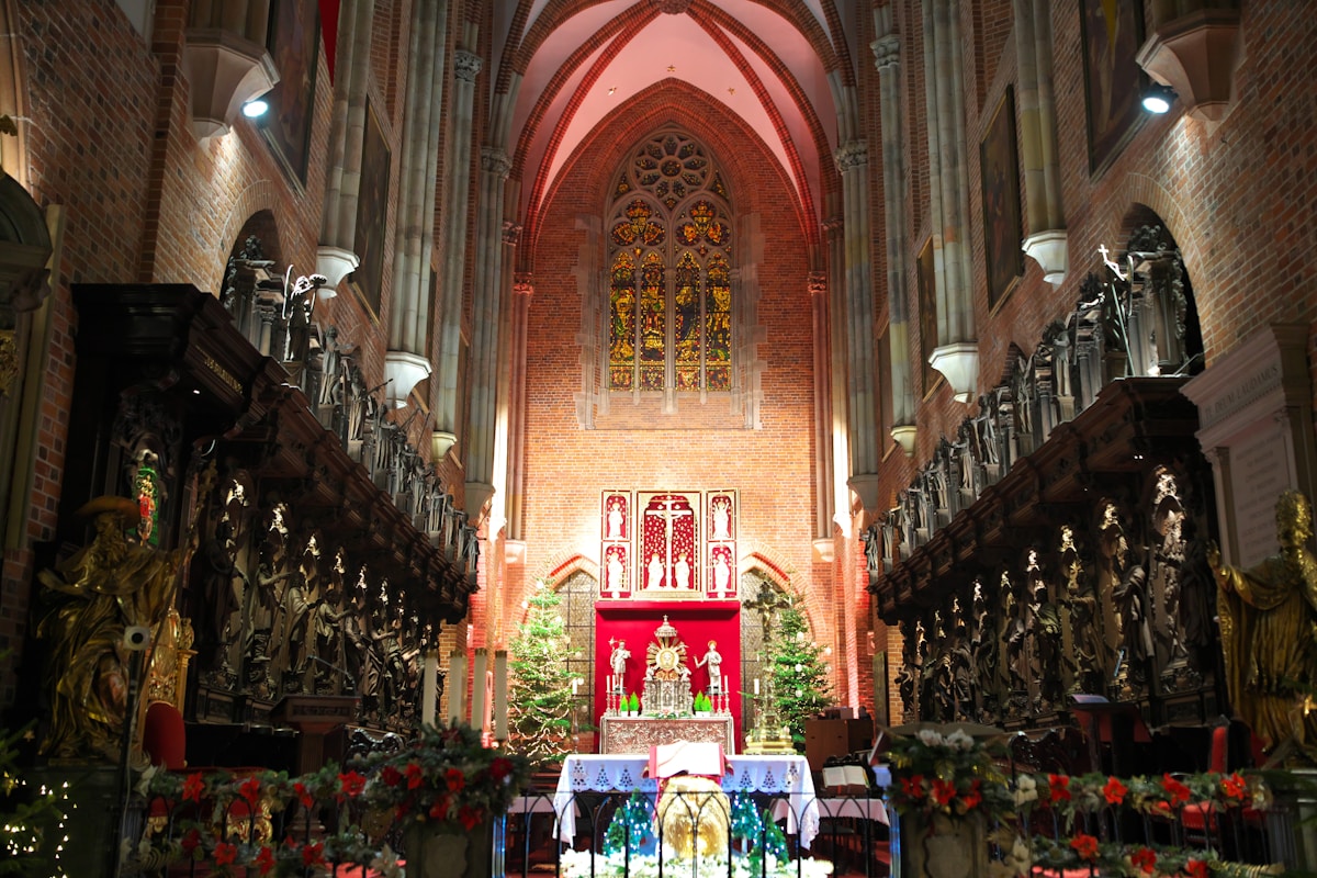 Intérieur d'une cathédrale gothique ornée pour Noël, avec vitraux colorés et décorations festives.