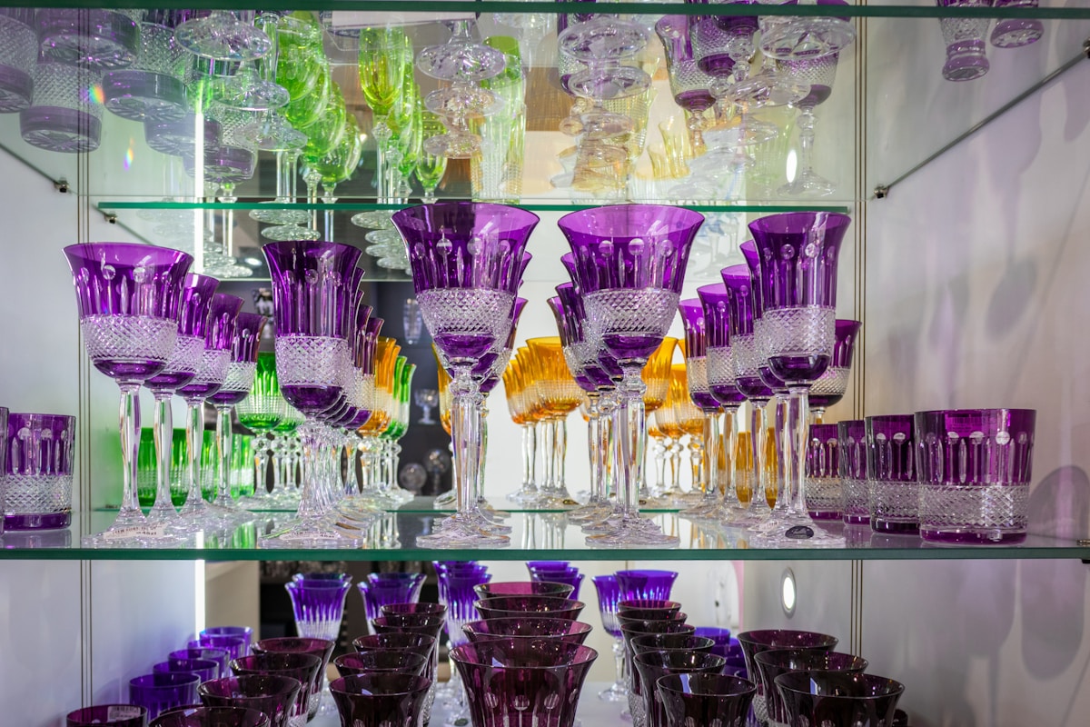 Verres de cristal violets et jaunes sur étagères en verre.