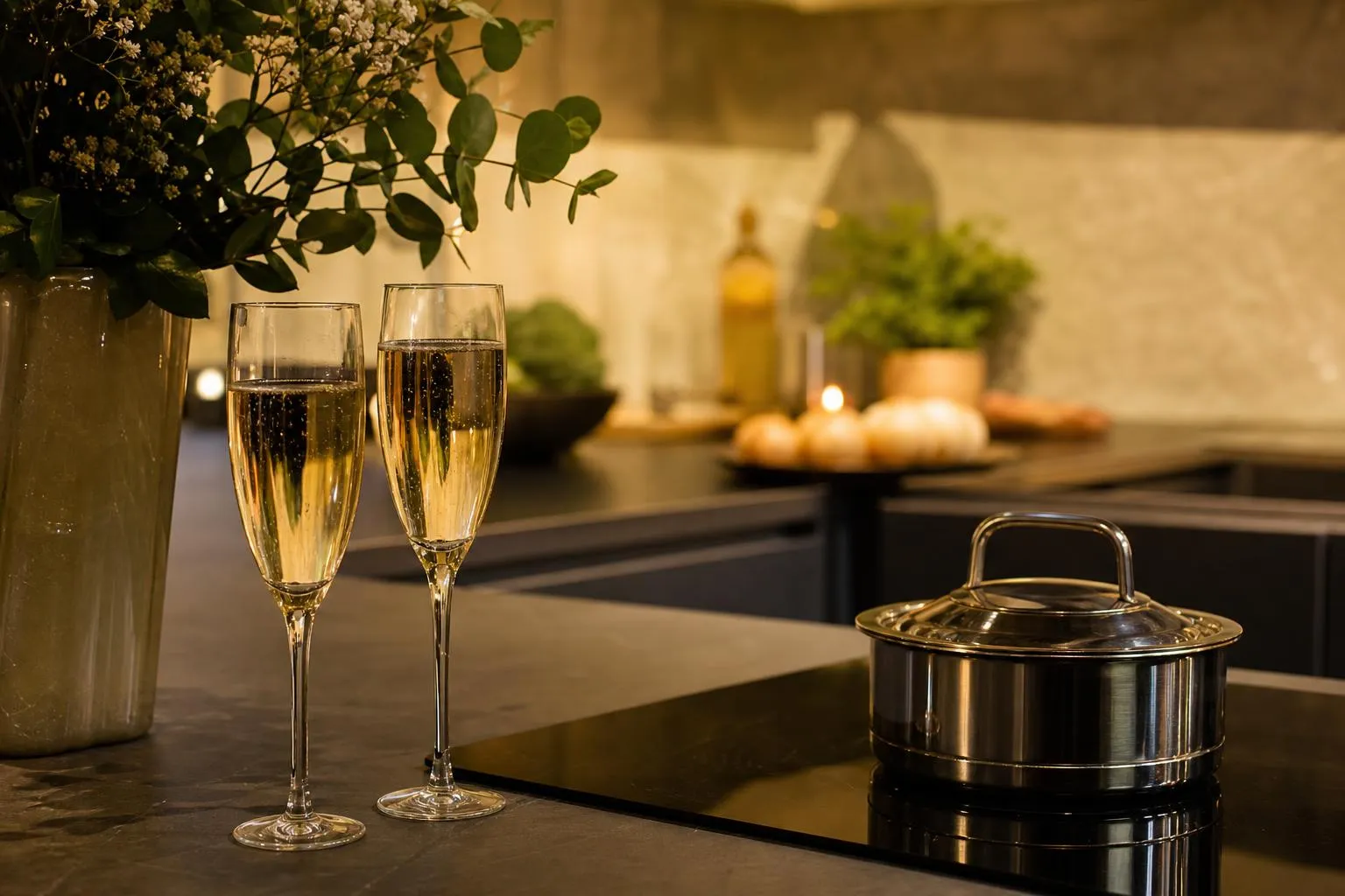 Deux flûtes de champagne, plat de fruits et bougie sur une table sombre.