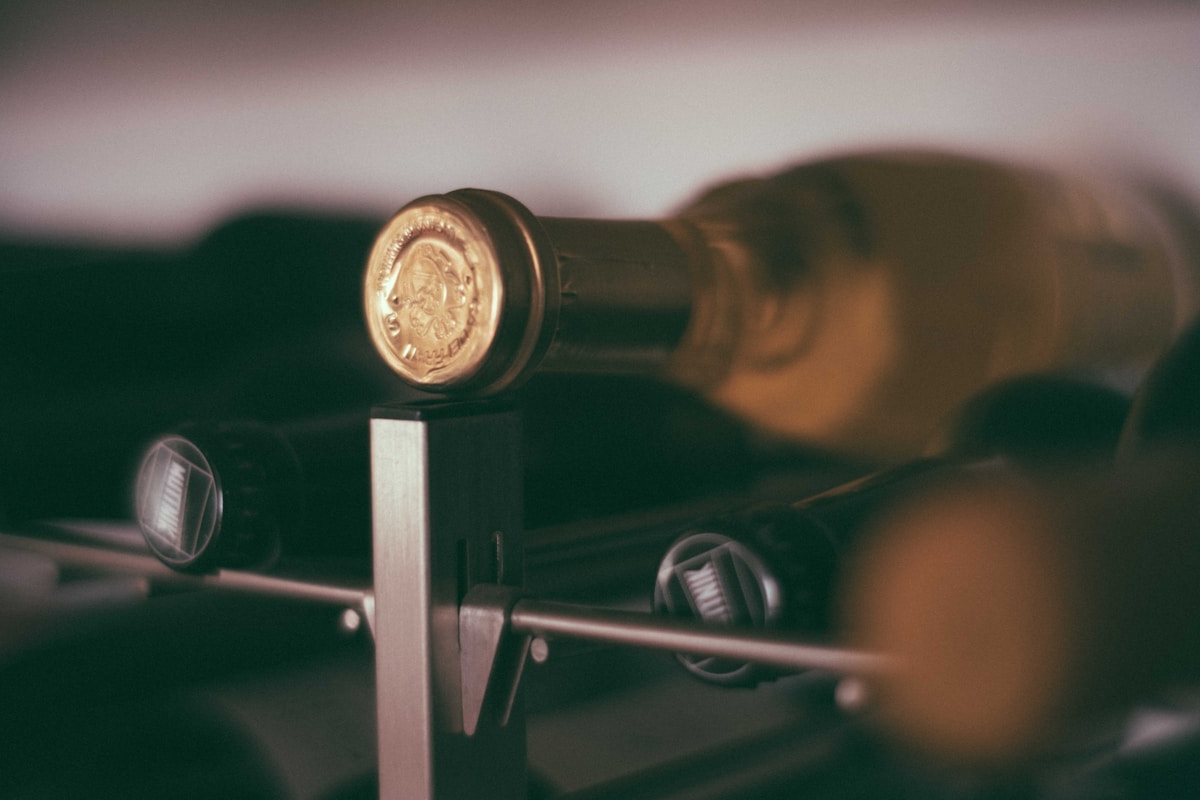 Bouteille de vin vintage sur étagère sombre.