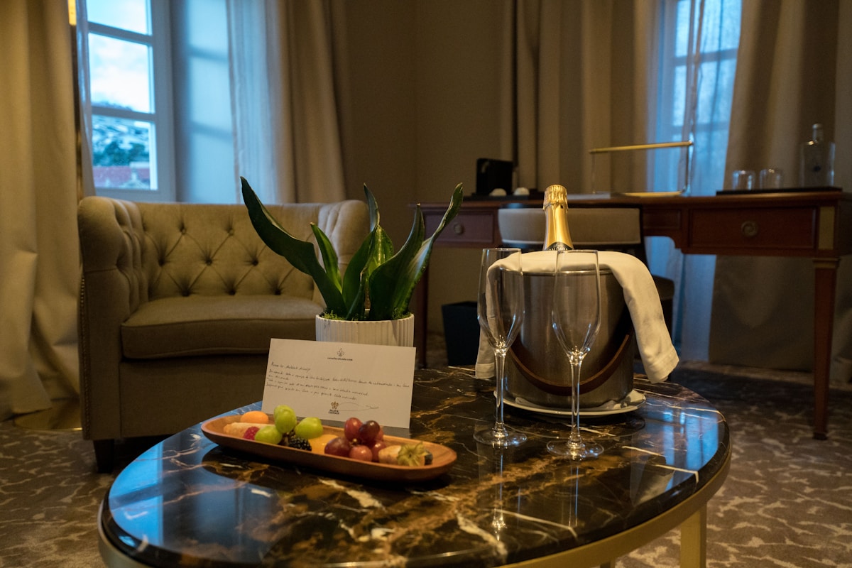 Salon élégant avec canapé capitonné, plante verte, champagne et fruits.