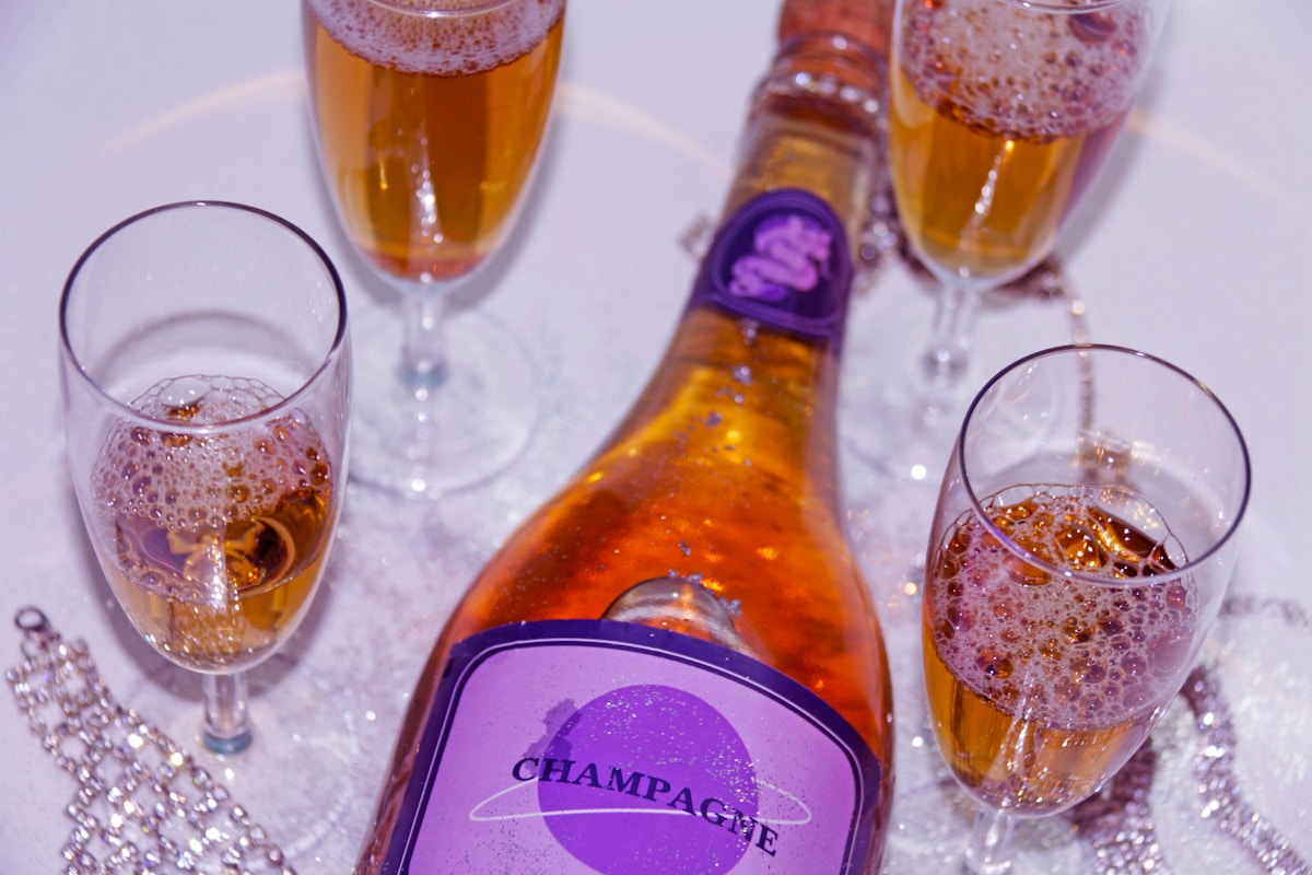 Bouteille de champagne violette avec verres remplis de boisson effervescente.